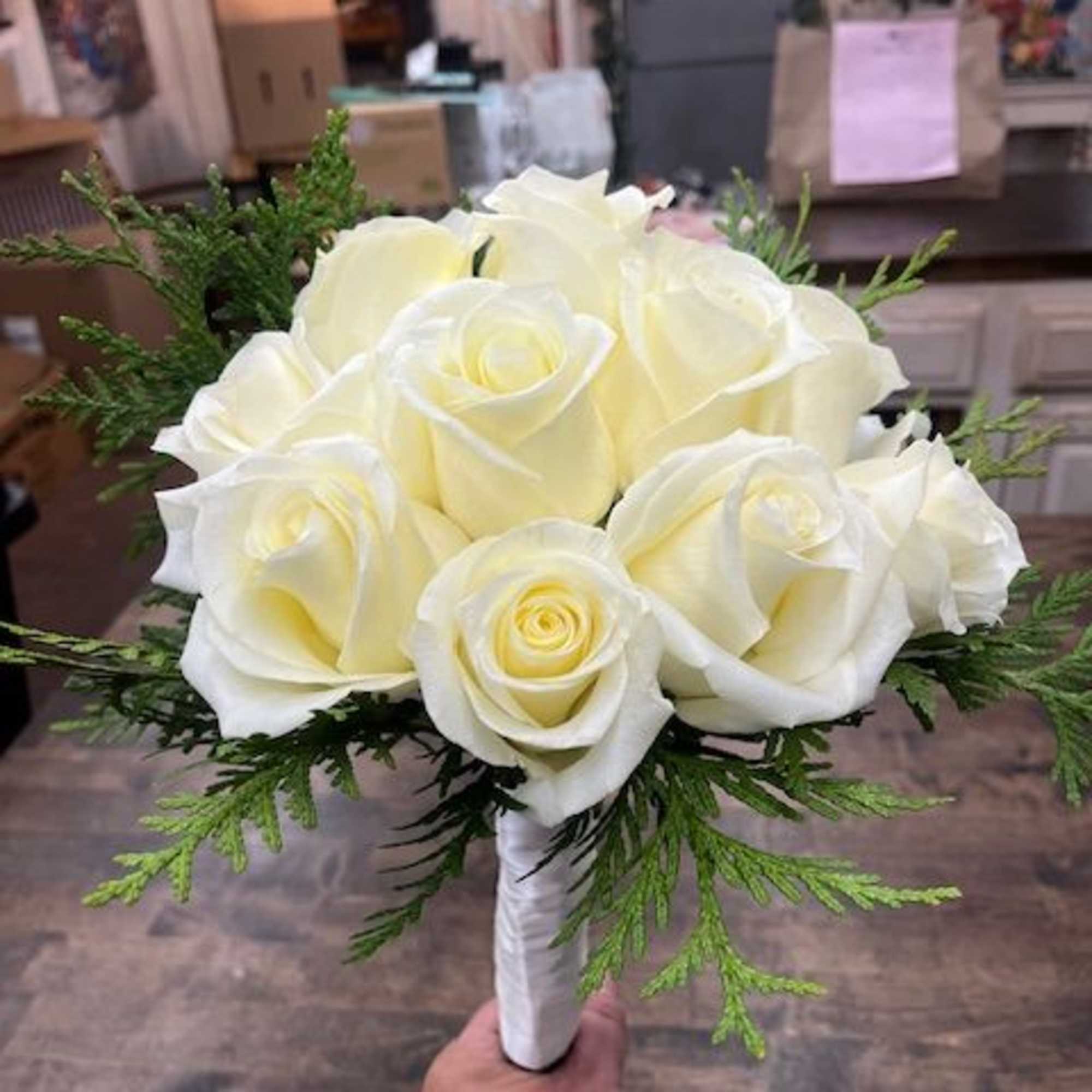 White rose bouquet with greenery, wrapped in white ribbon