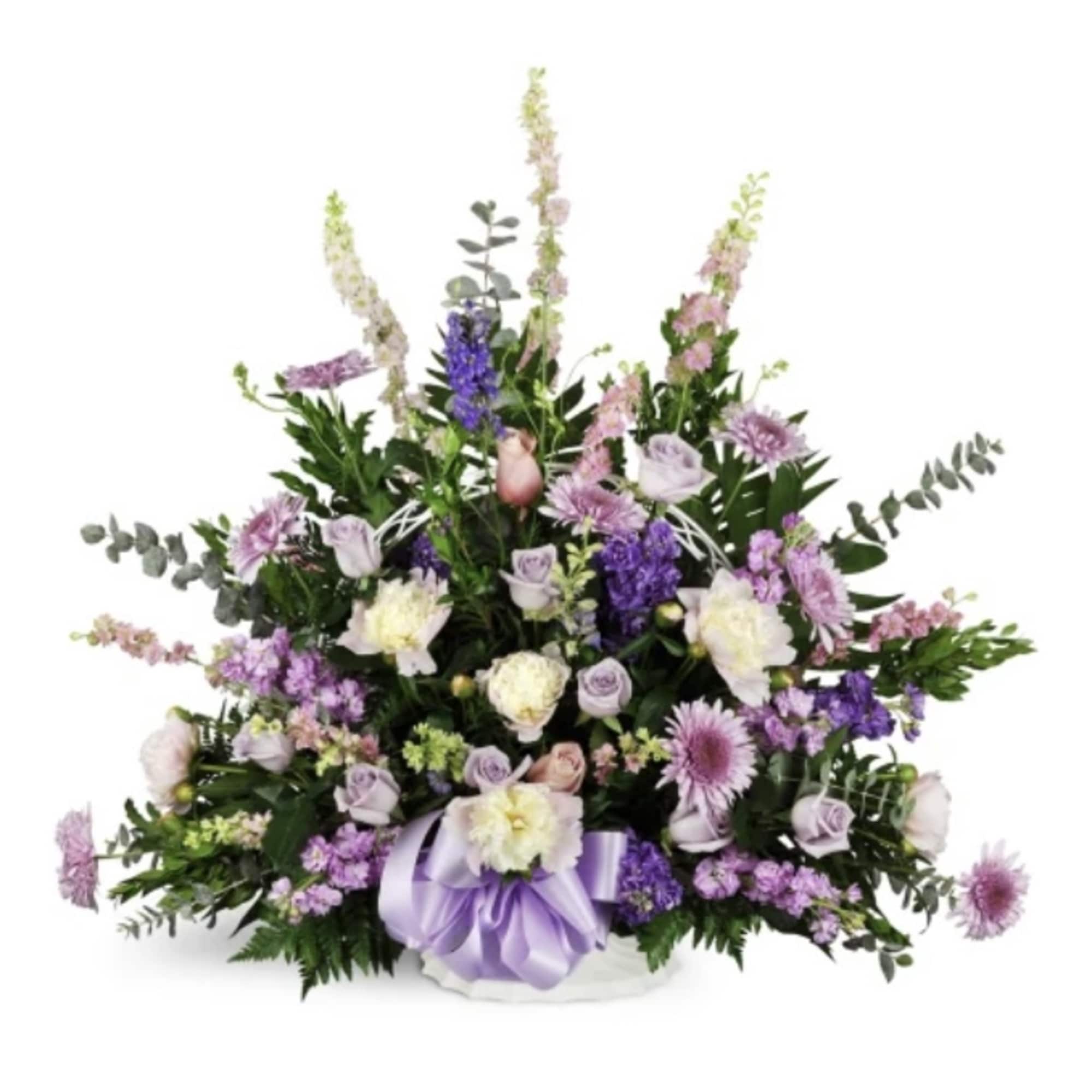 Lavender and white floral arrangement in a white basket with a purple ribbon