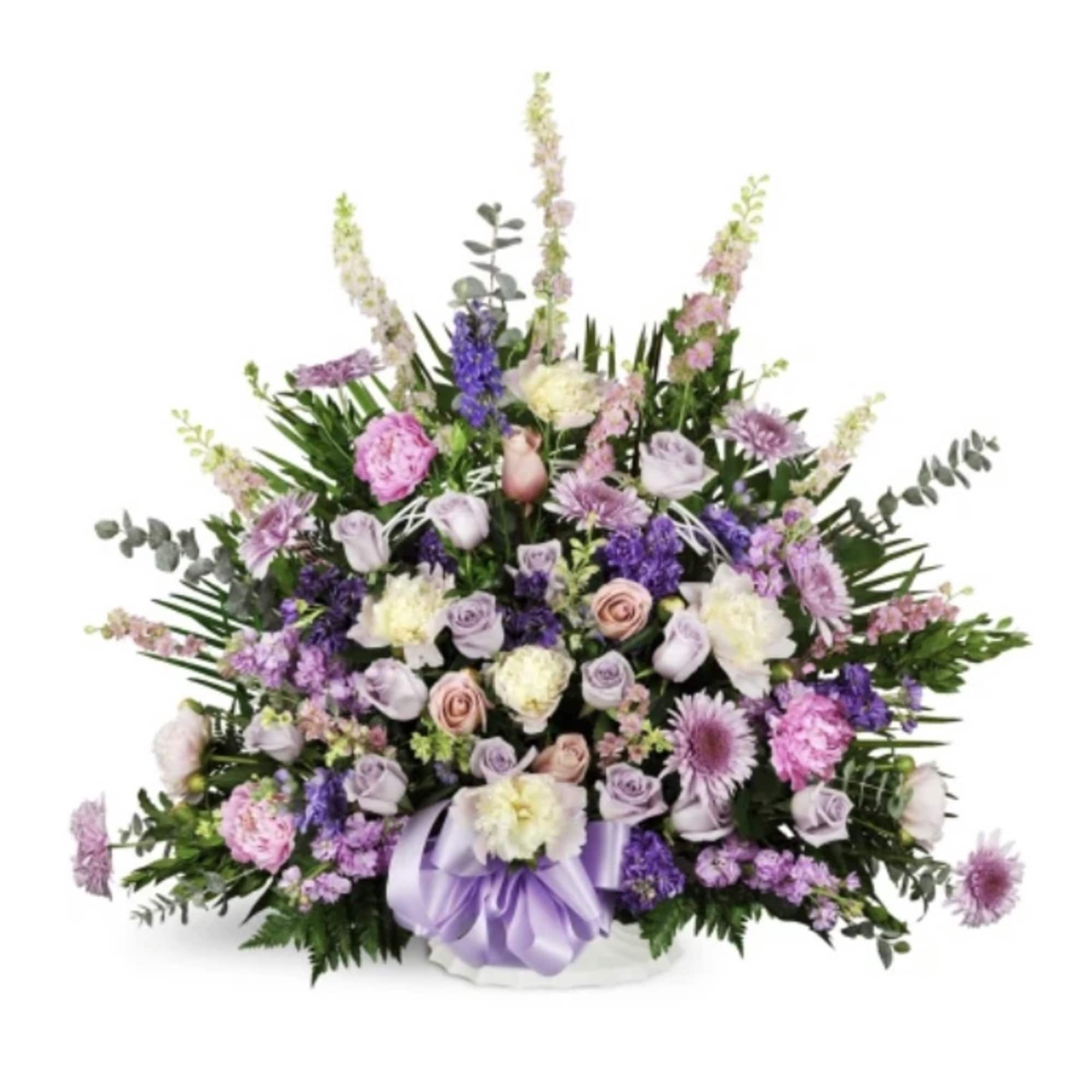 Lavender and pink floral arrangement in a white container with a purple ribbon