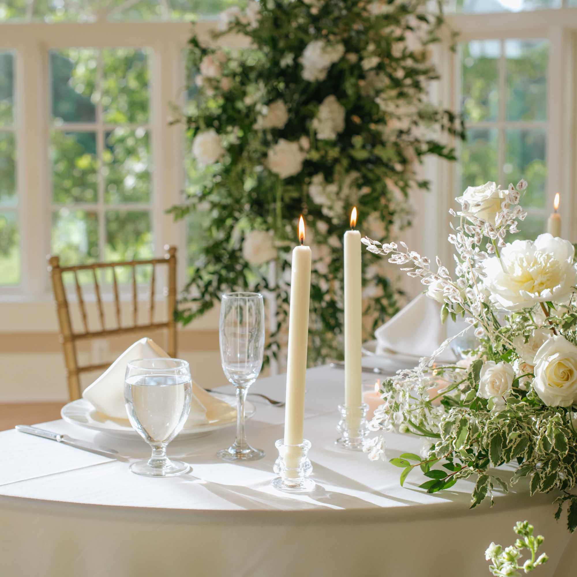 White floral centerpiece with candles on a table set for an event