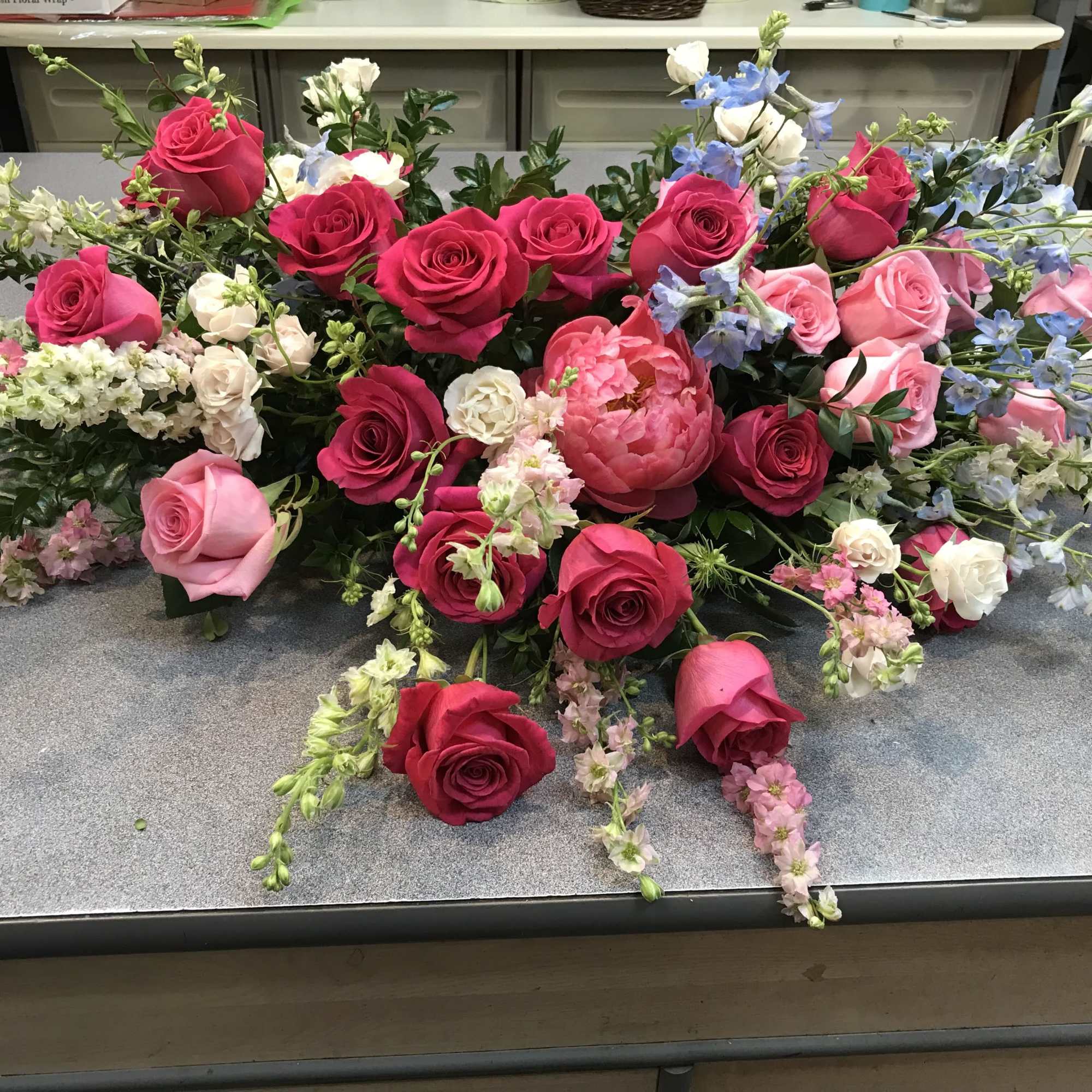 Loose floral arrangement of pink and red roses with blue and white flowers