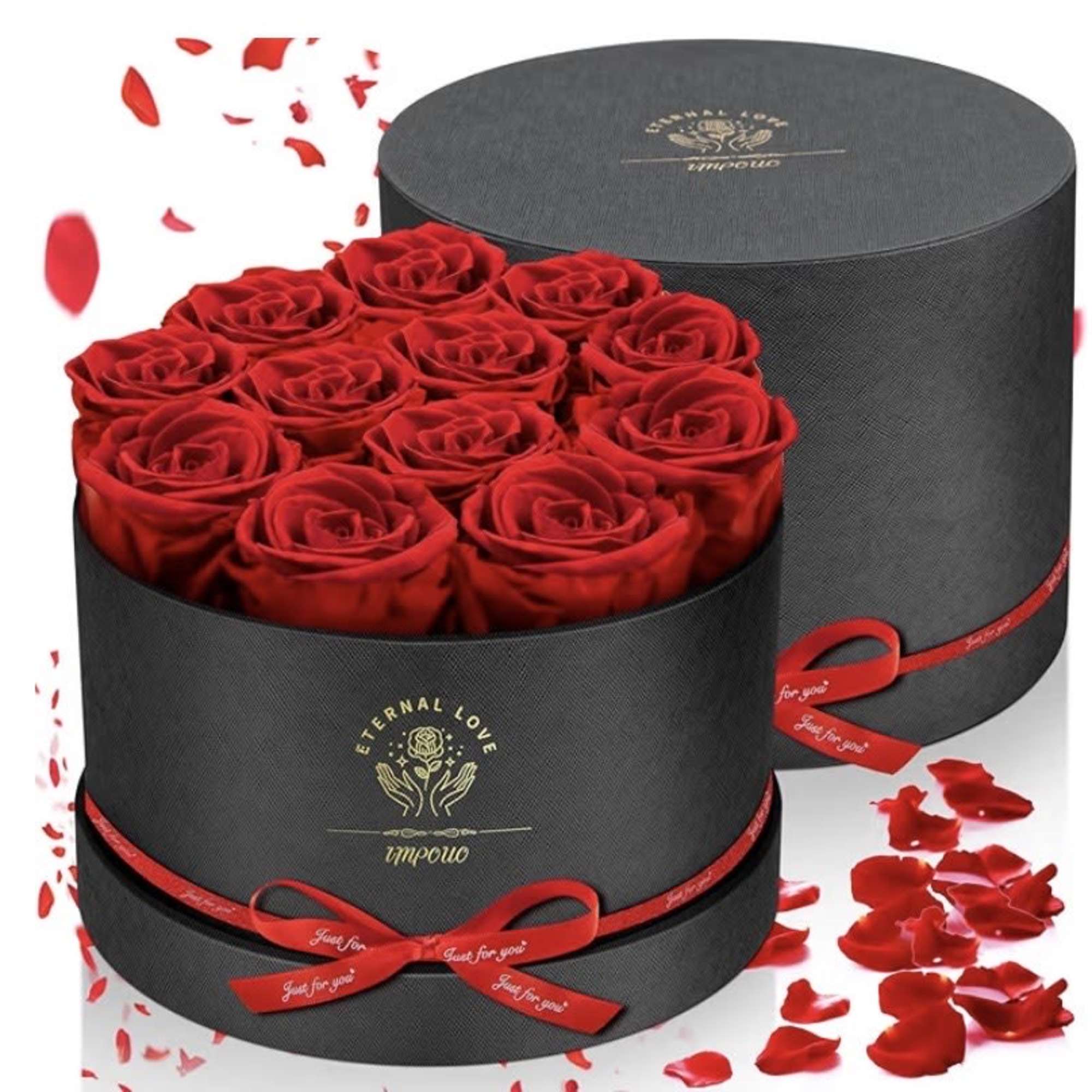 Red roses arranged in black round gift boxes with red ribbon and scattered petals