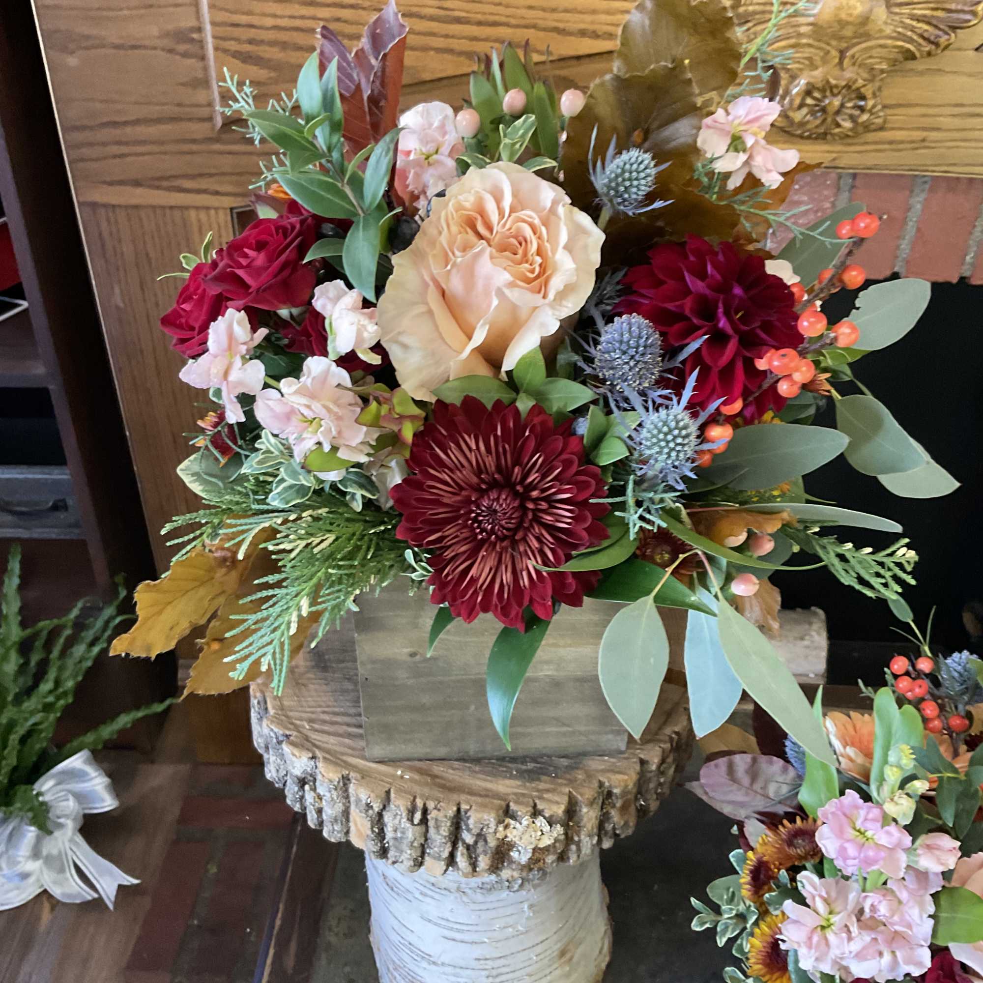 Arrangement of red and peach flowers in a rustic wooden container