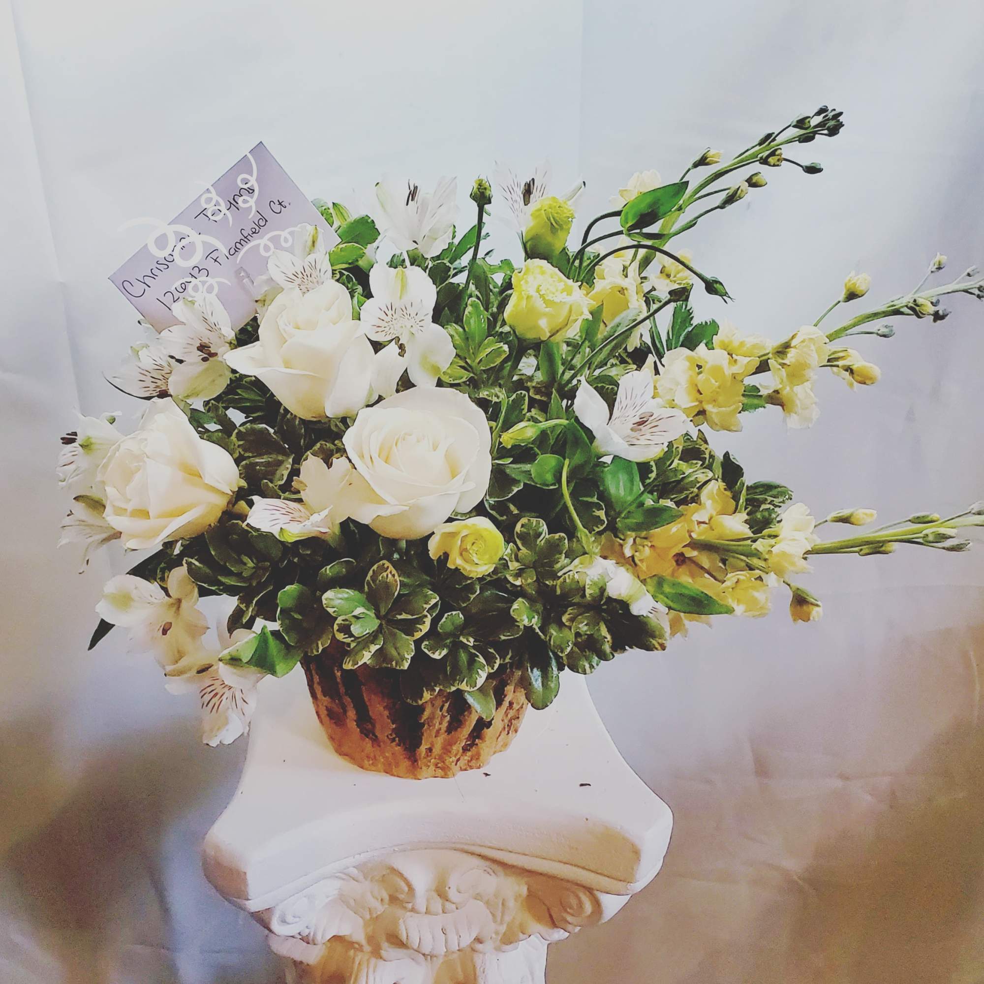 White roses and pale yellow flowers arranged in a rustic vase