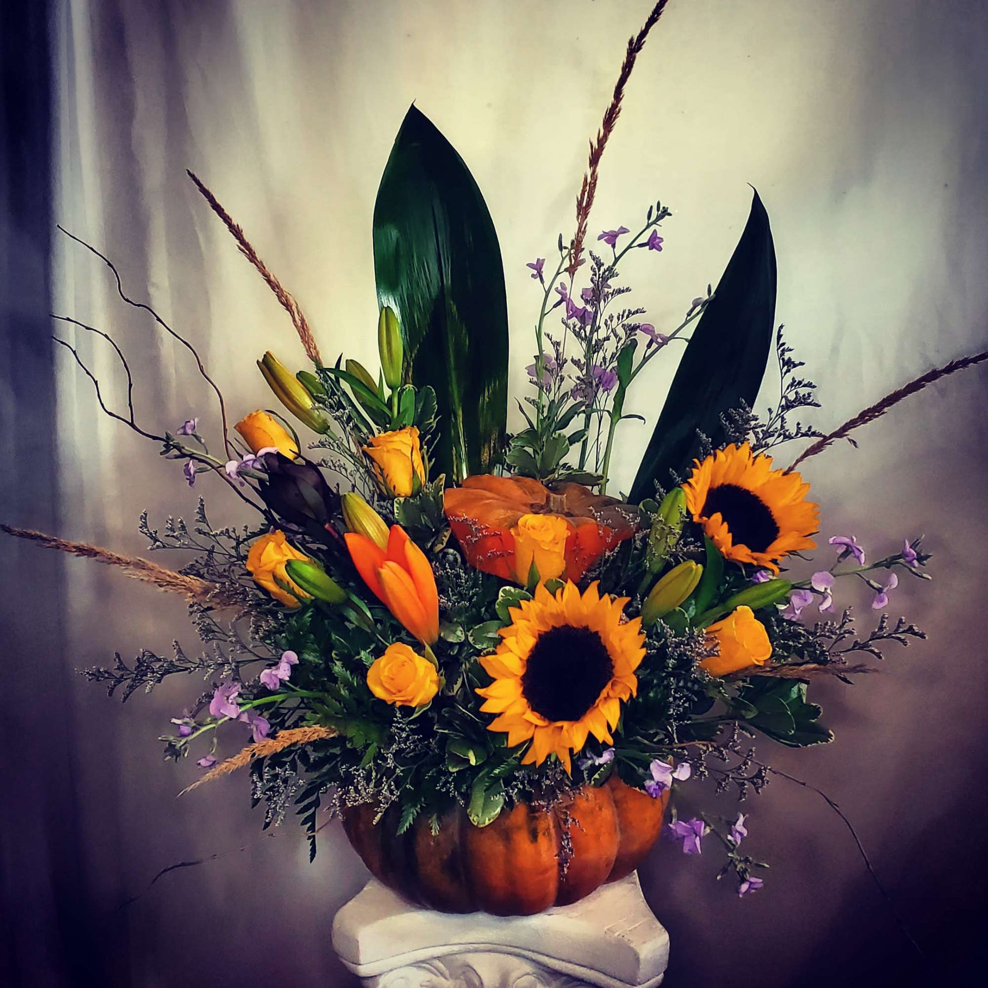 Sunflowers and orange roses arranged in a pumpkin container