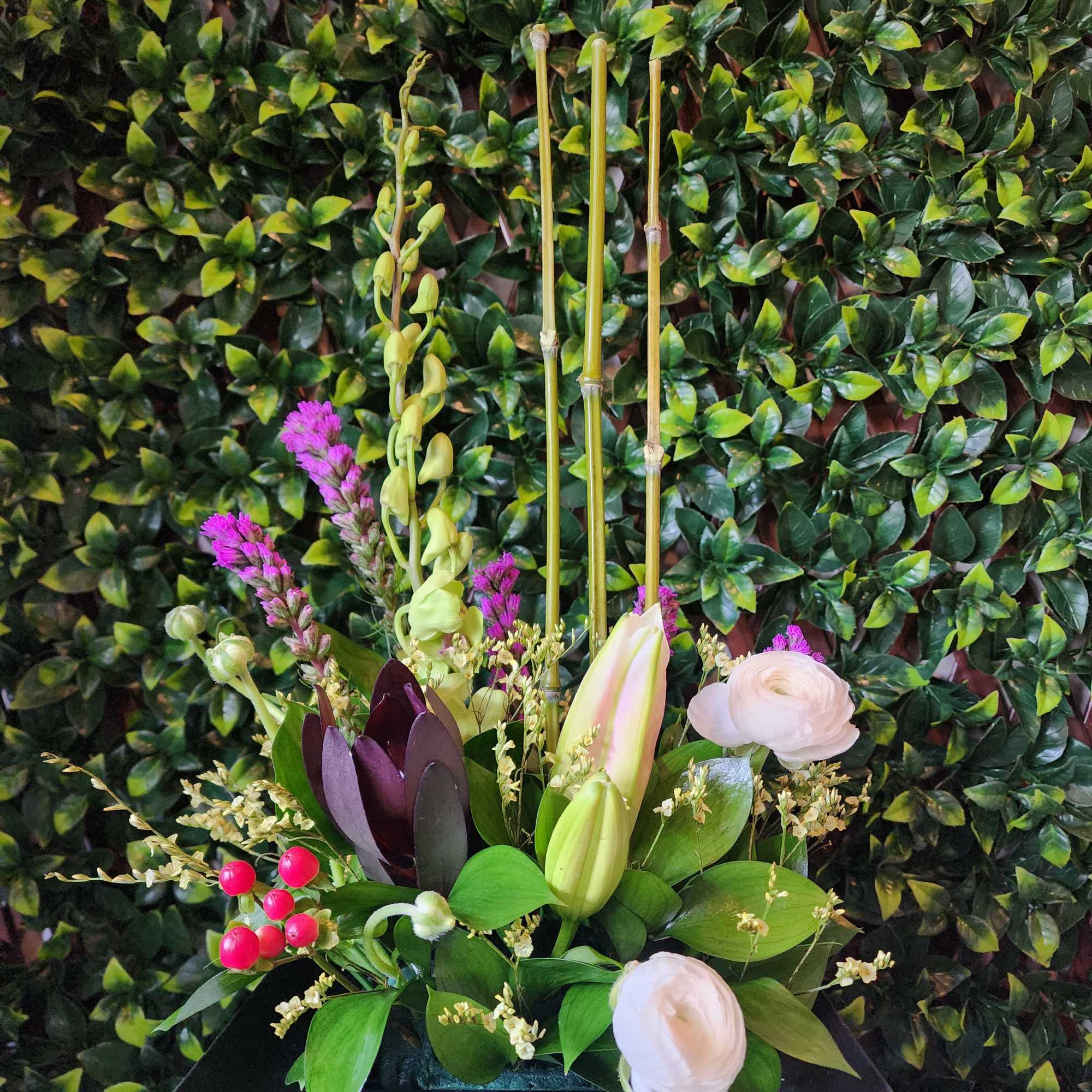 Mixed floral arrangement in a black rectangular container with tall stems