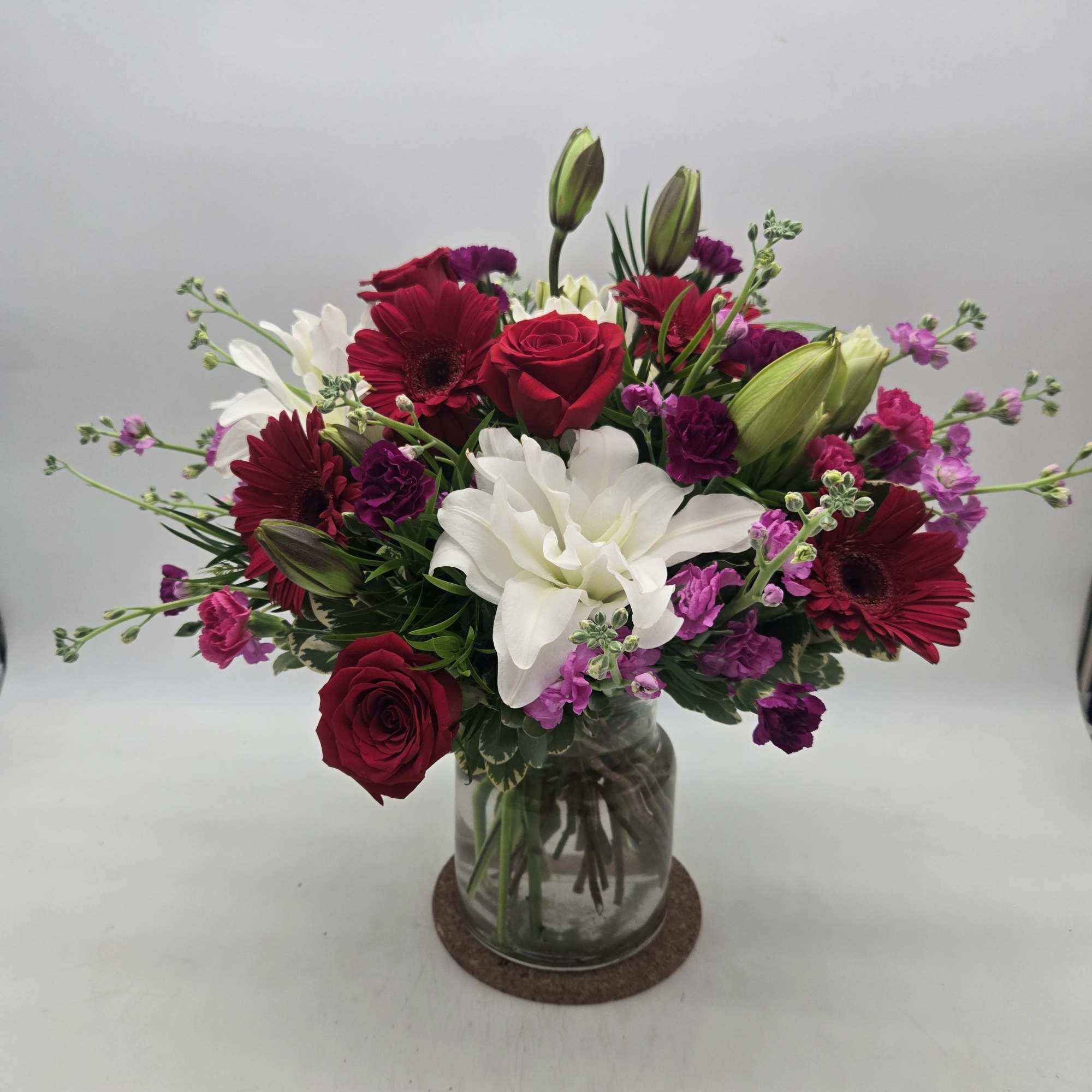 Mixed bouquet of red, white, and purple flowers in a glass vase