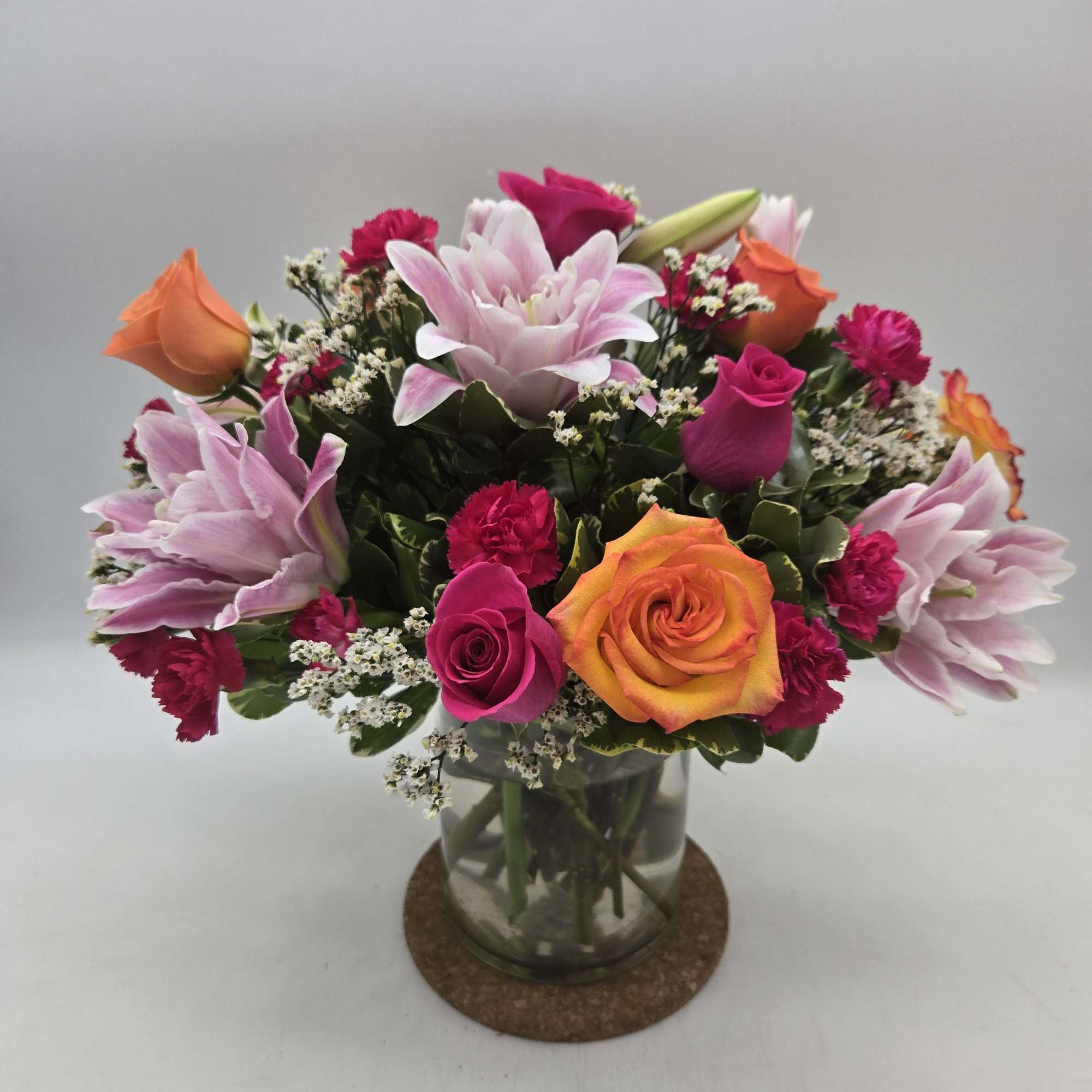 A dazzling cluster of pink lilies and vibrant orange roses makes a