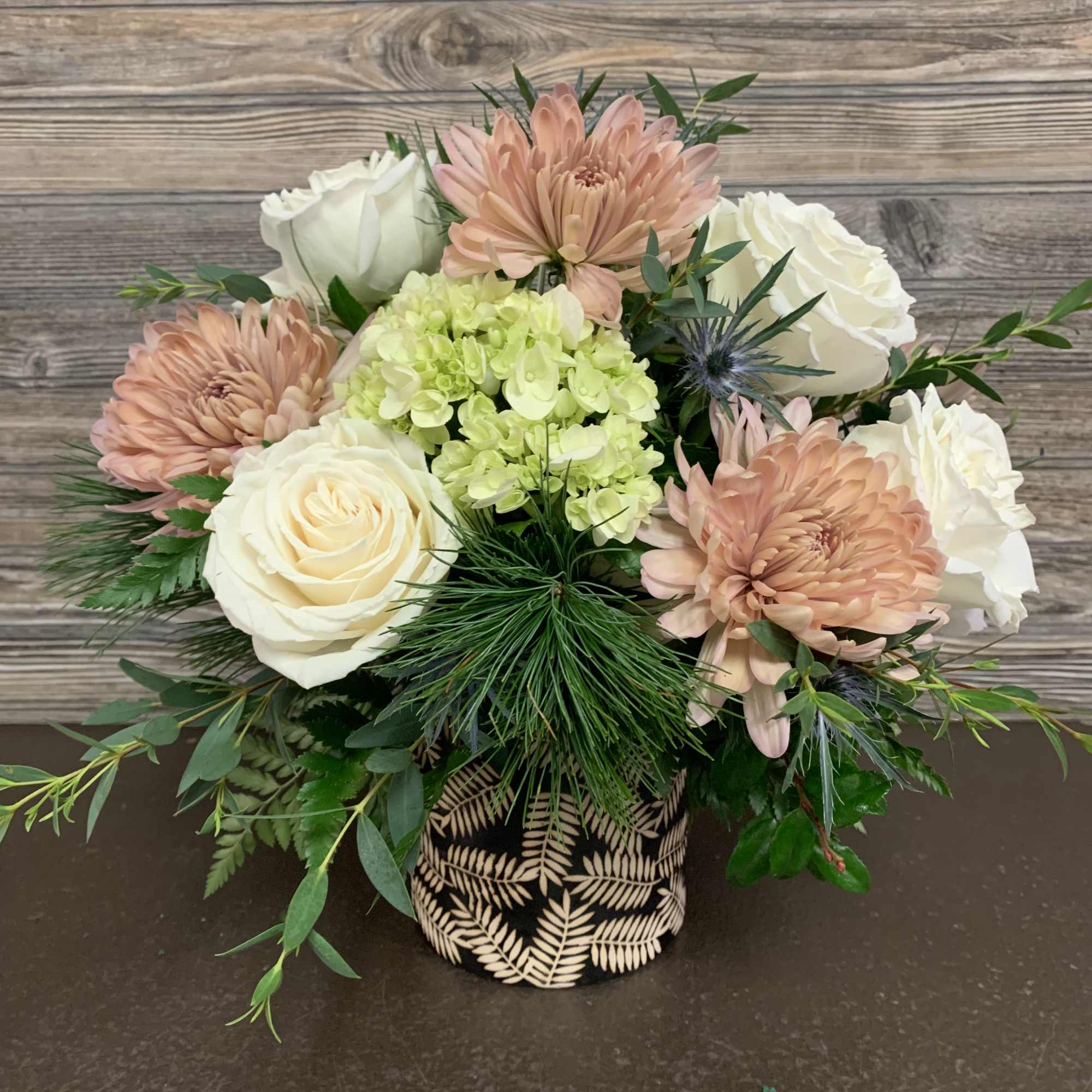 Soft palette of peach mums, white roses, green hydrangeas, blue thistle accented