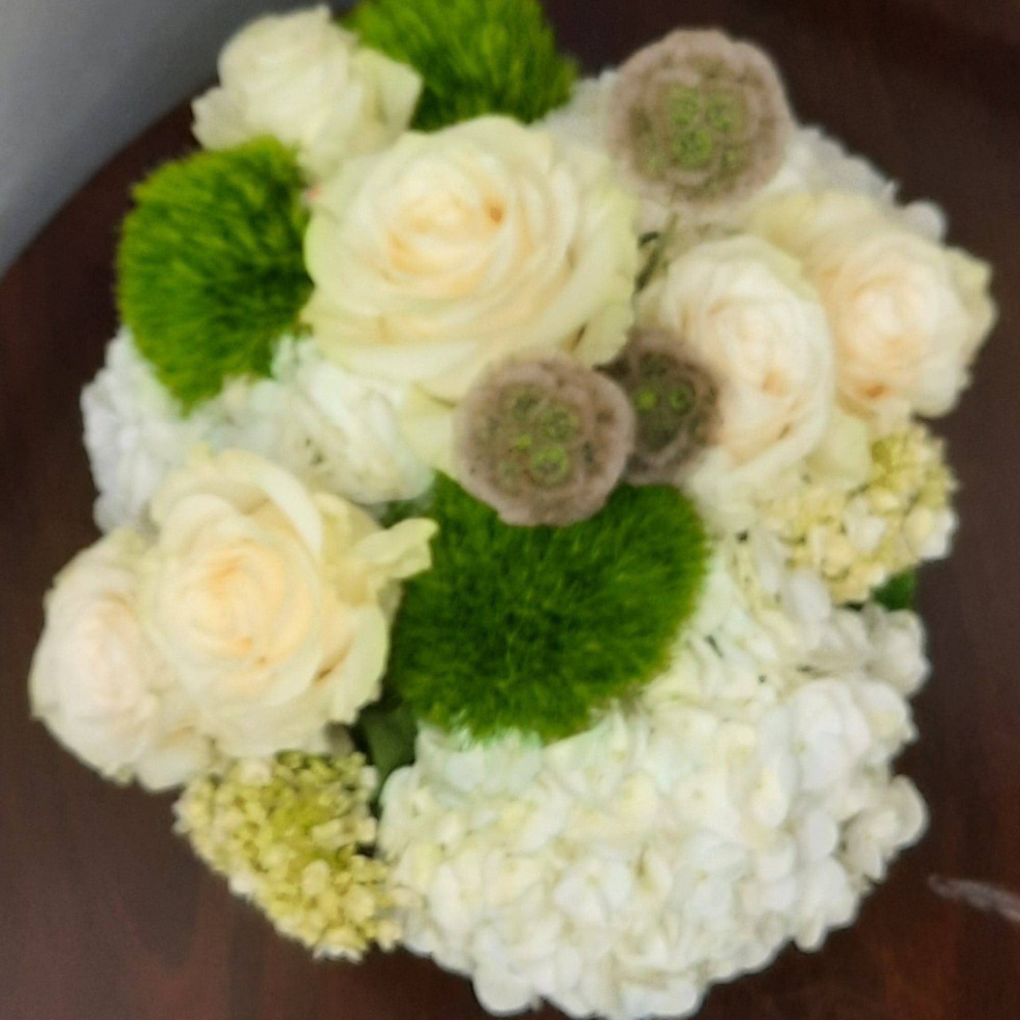 White roses and hydrangeas with bright green pom-poms in a round bouquet