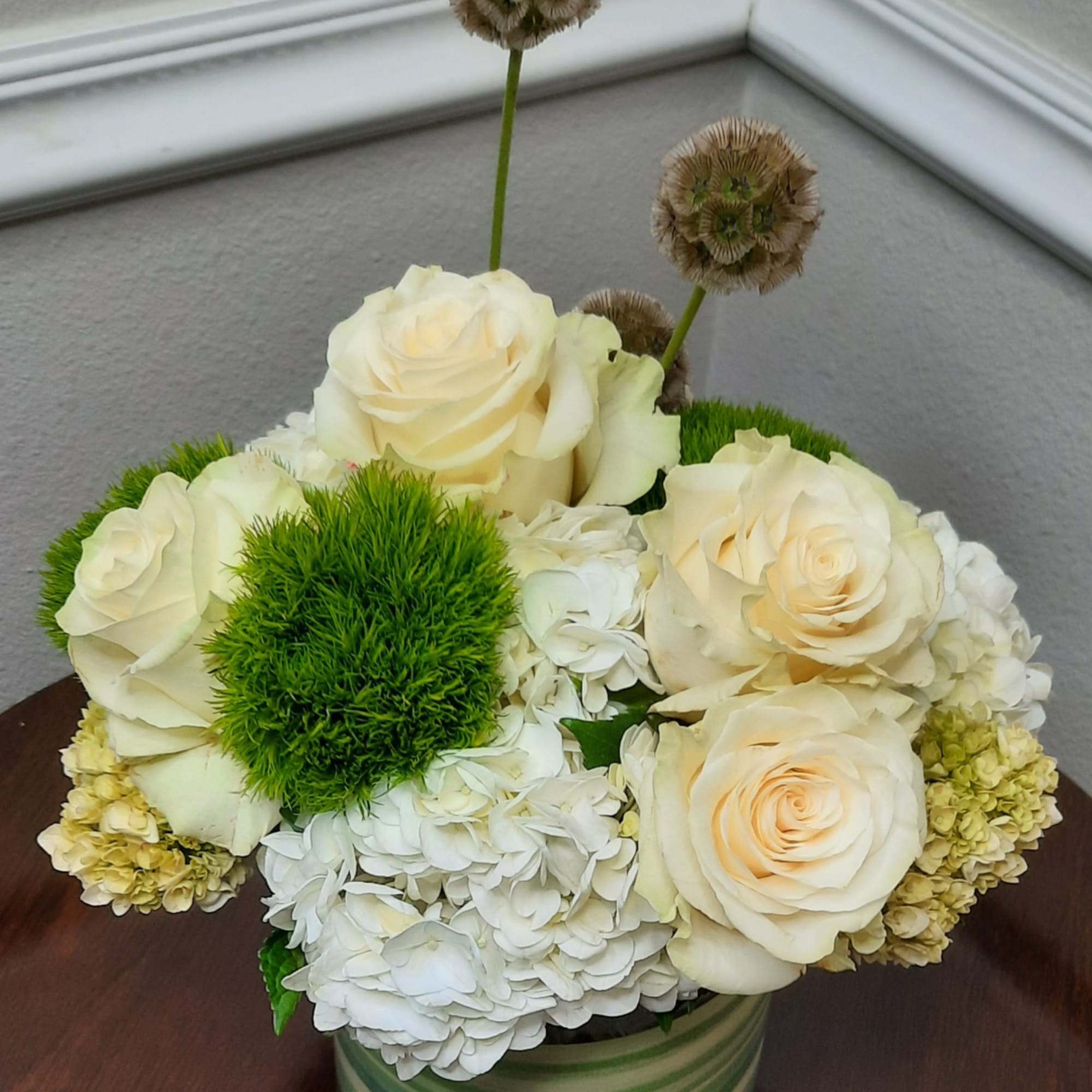 Cream roses and white hydrangeas arranged in a striped vase