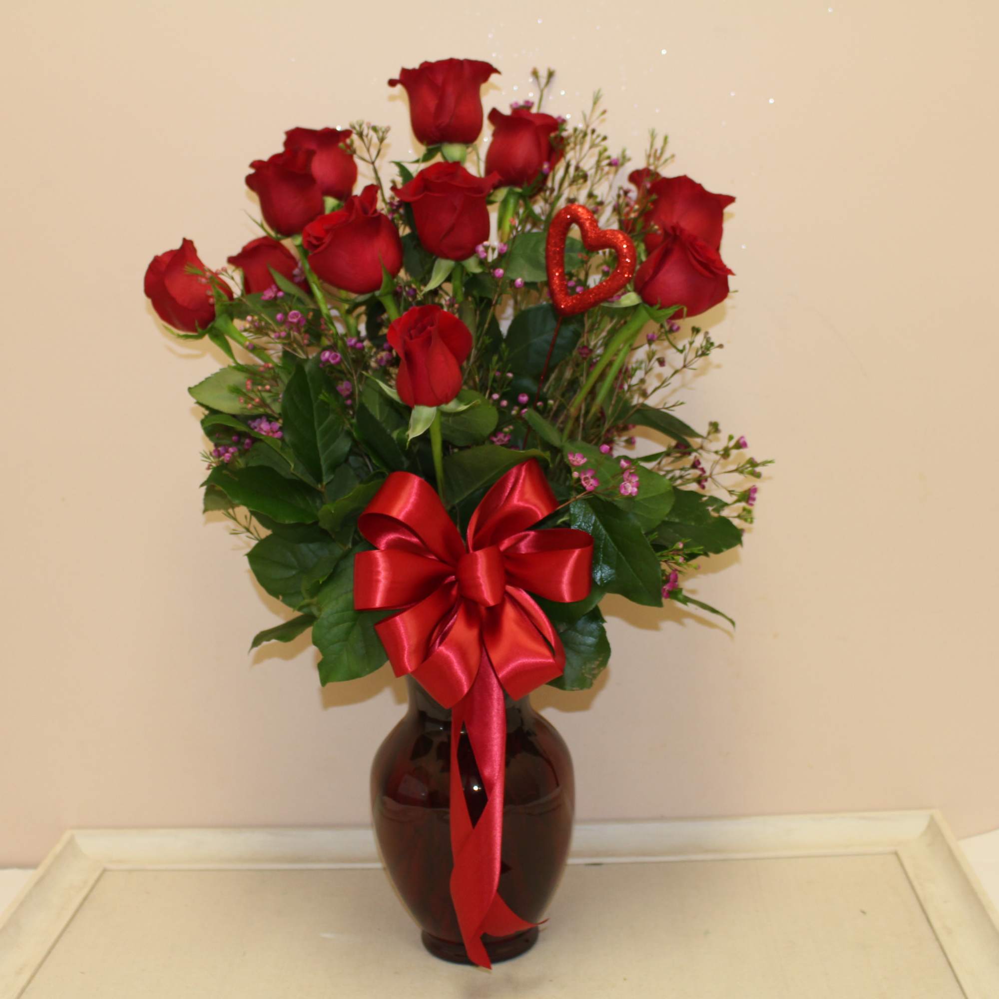 Red roses in a dark vase with a red ribbon bow