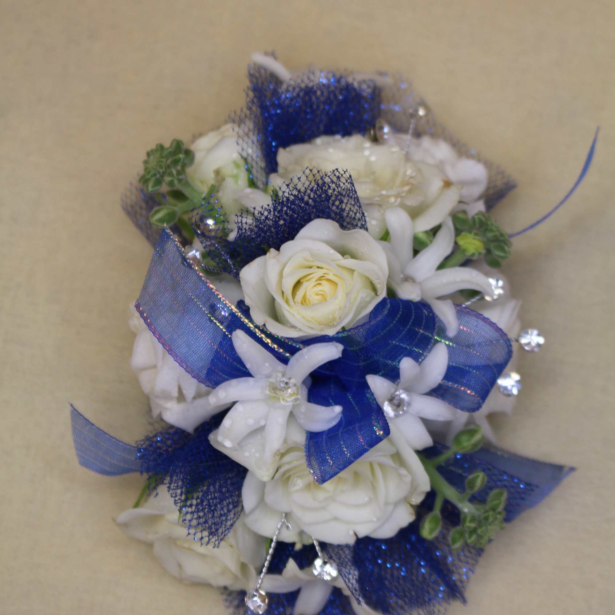 White rose corsage with blue ribbon and white accents