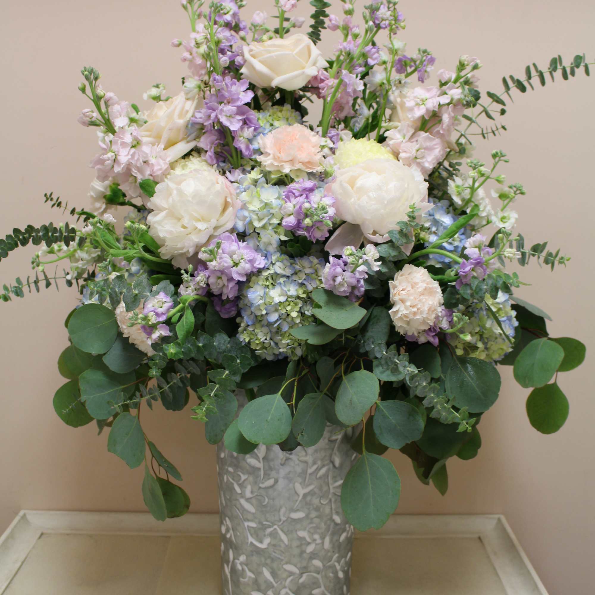 Large pastel flower arrangement in a silver vase
