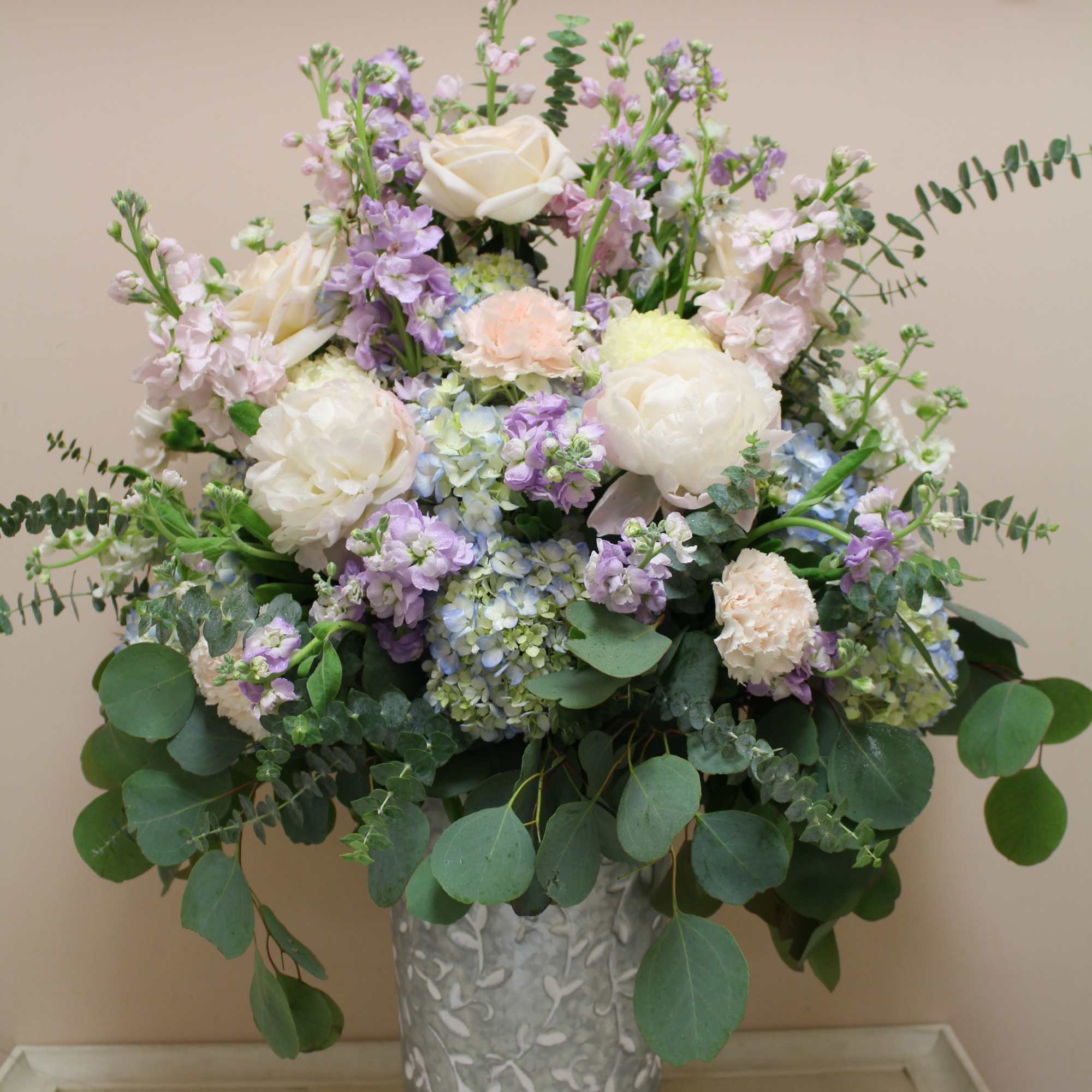 Pastel floral arrangement in a decorative metal vase