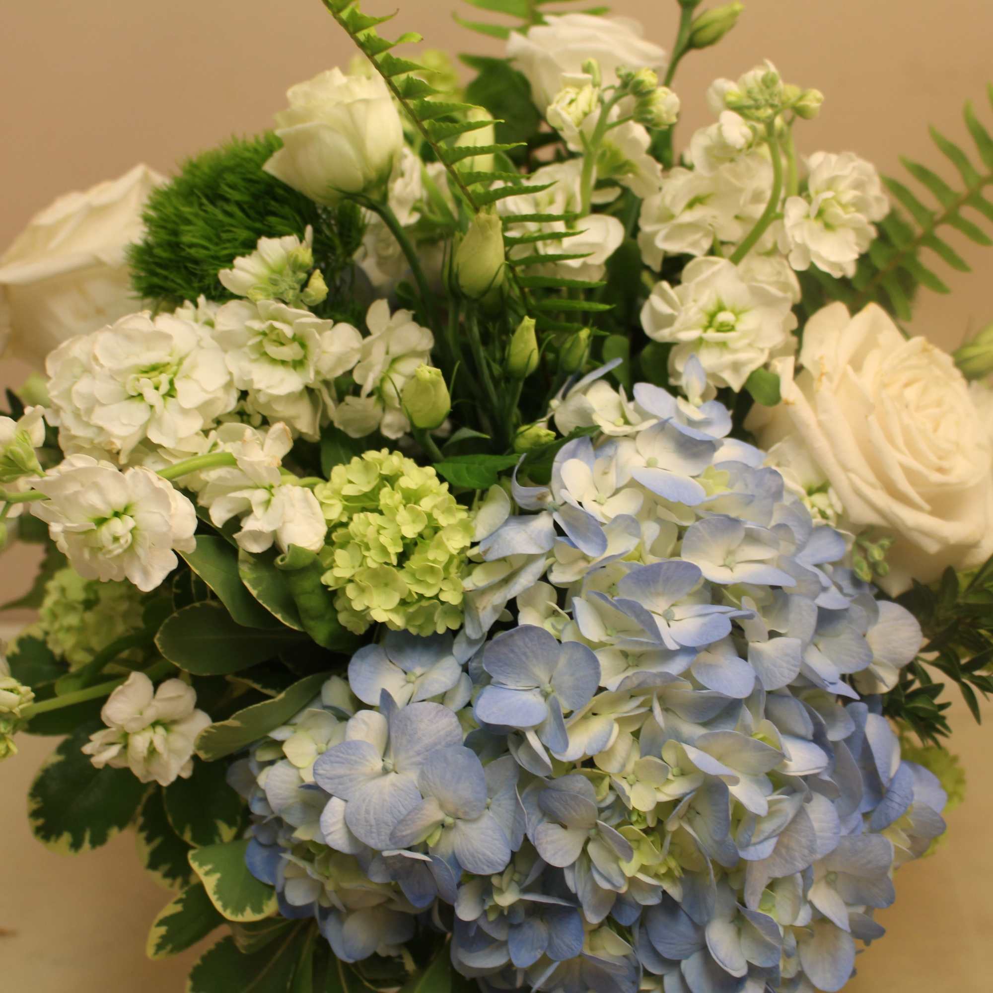 Bouquet of white roses, blue hydrangeas, and white stock flowers