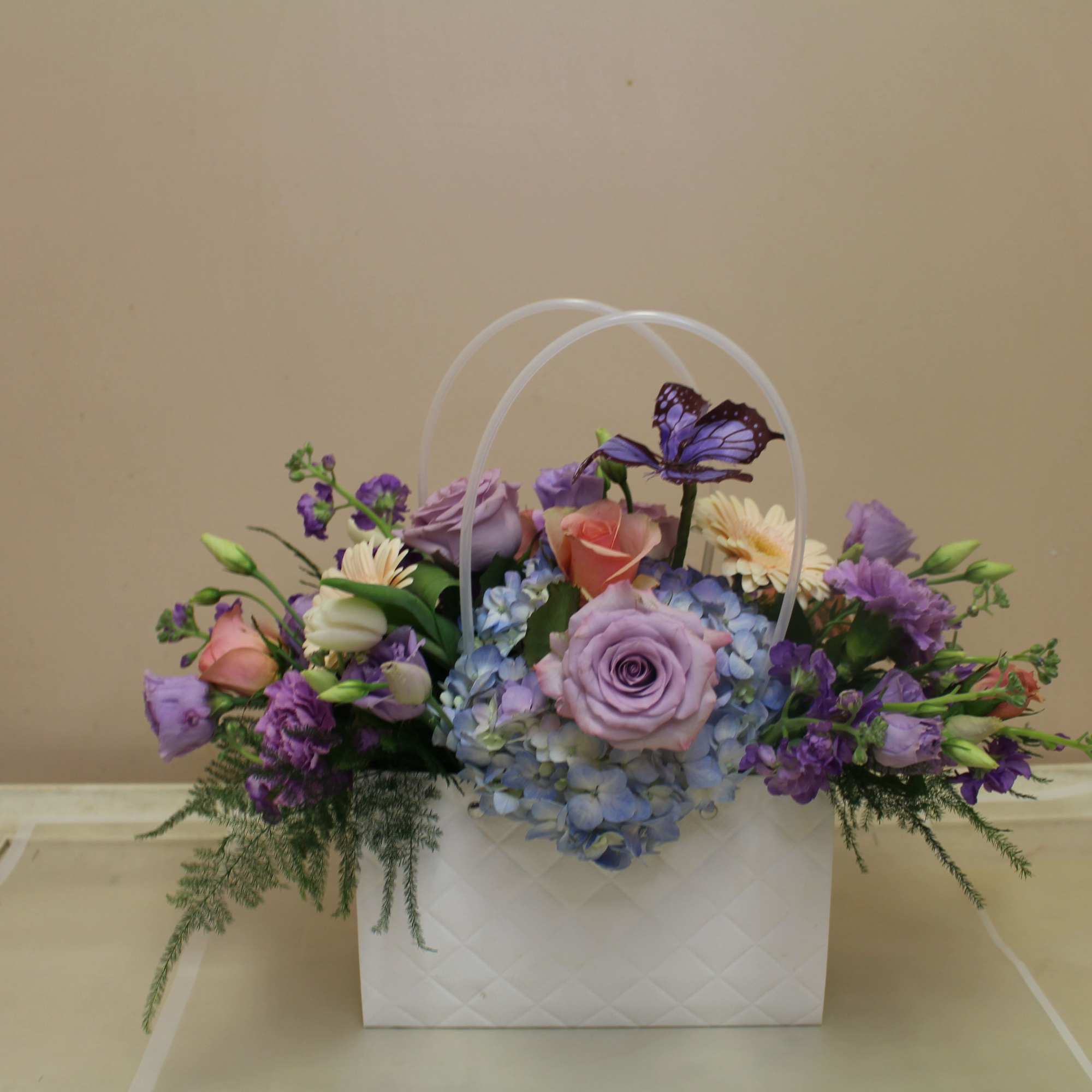 A soft pastel gift arrangement in a decorative white quilted pocketbook, this, photo 2 of 3
