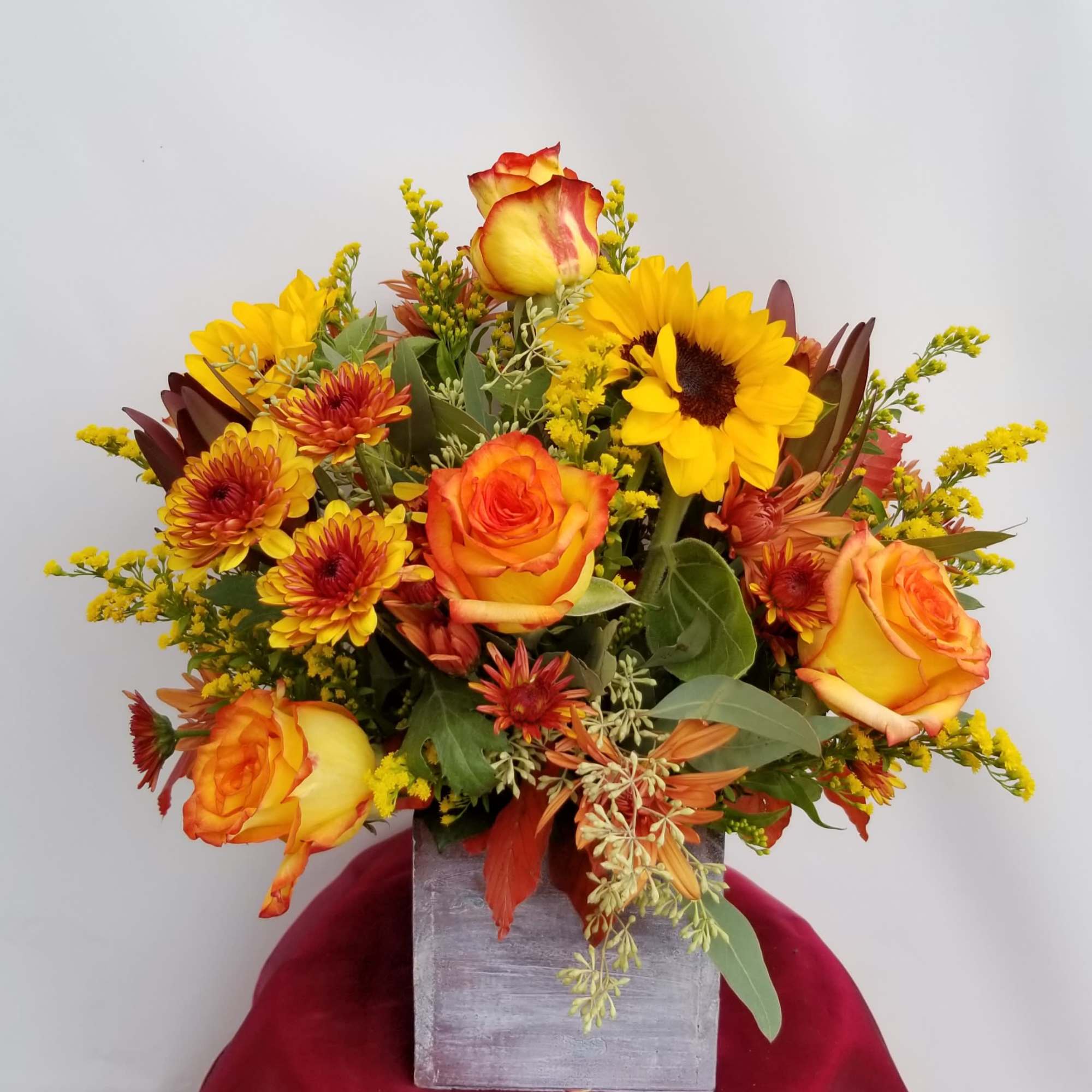 Orange and yellow bouquet in a square gray vase