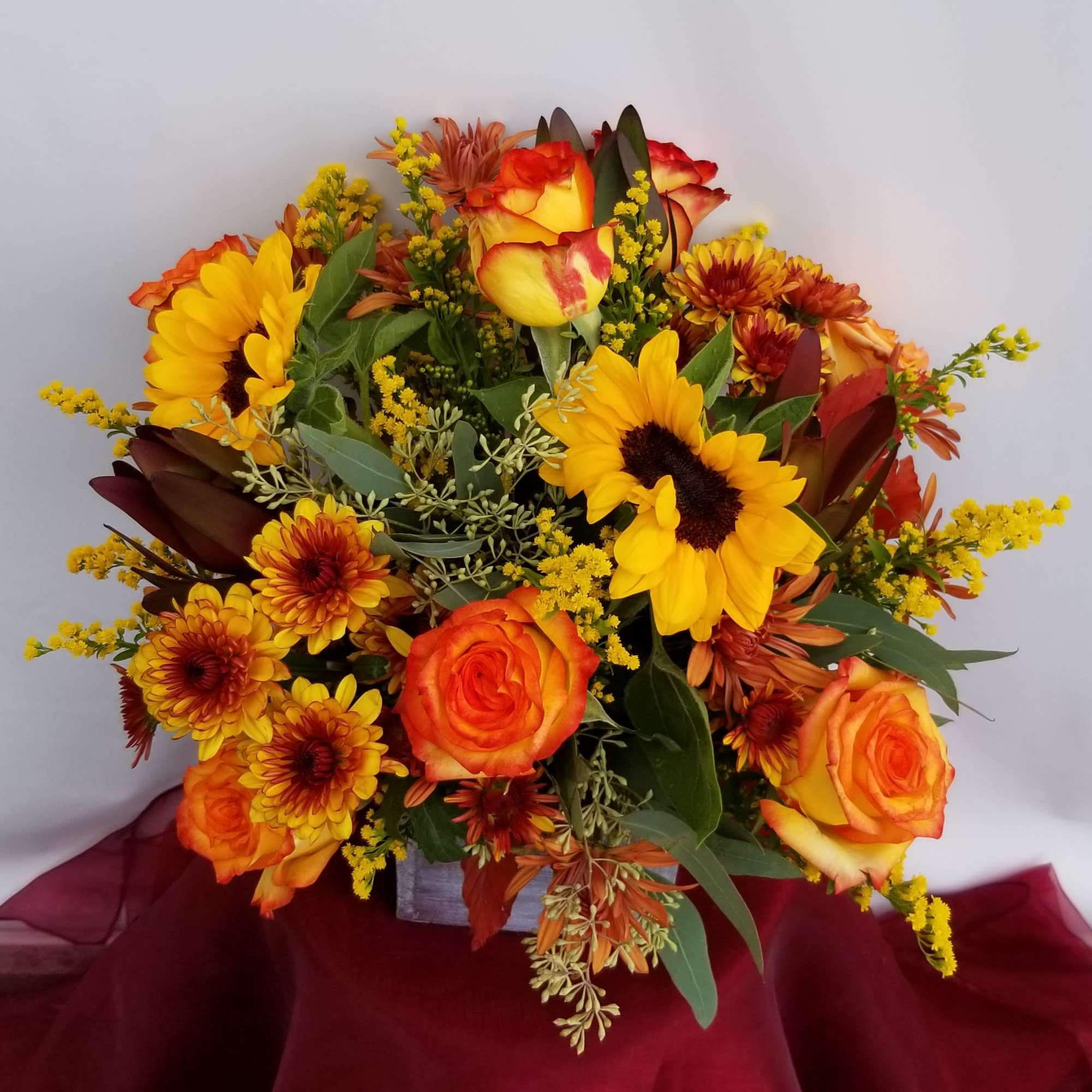 Bouquet of yellow sunflowers and orange roses in a square vase