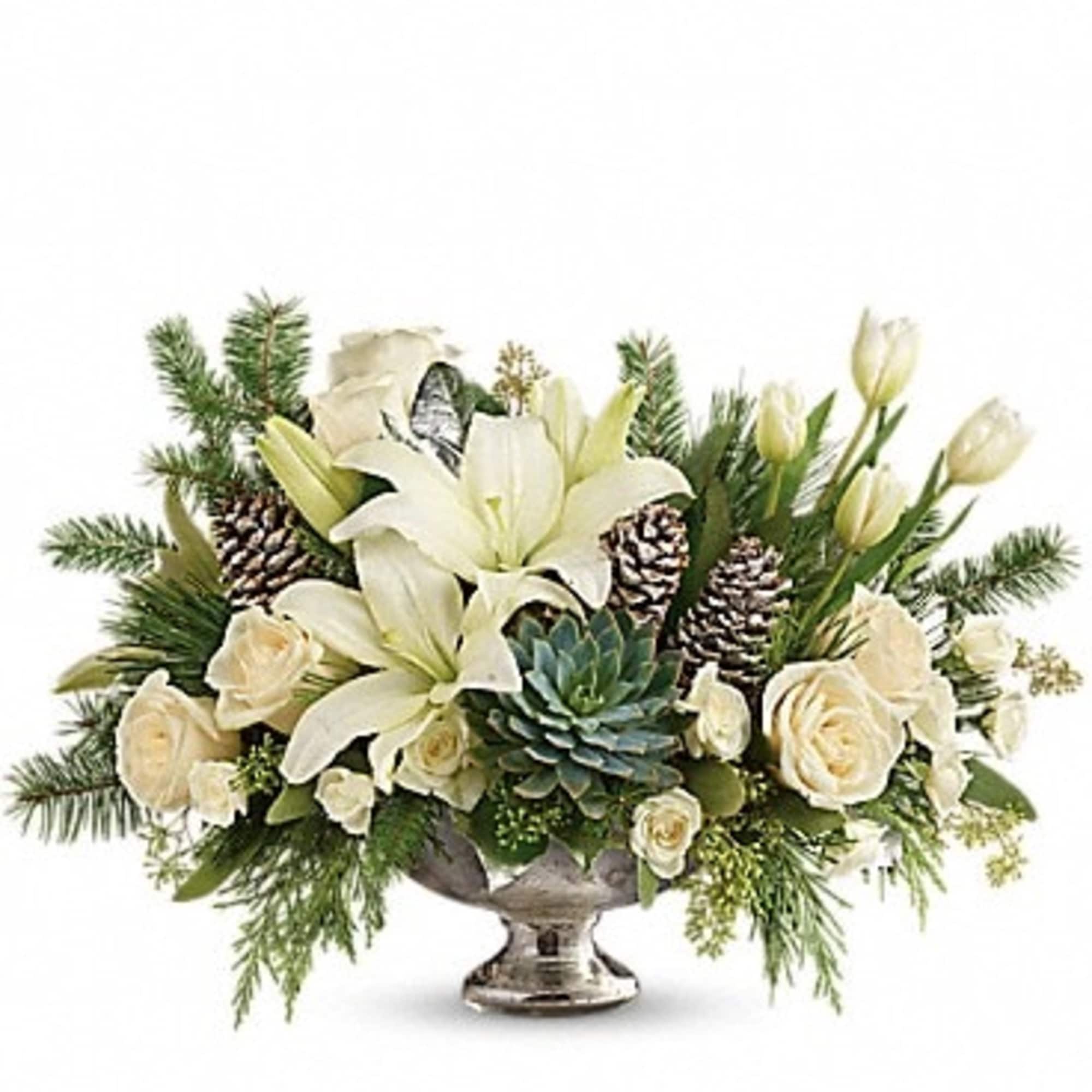 White lilies and roses arranged in a silver pedestal bowl with pinecones