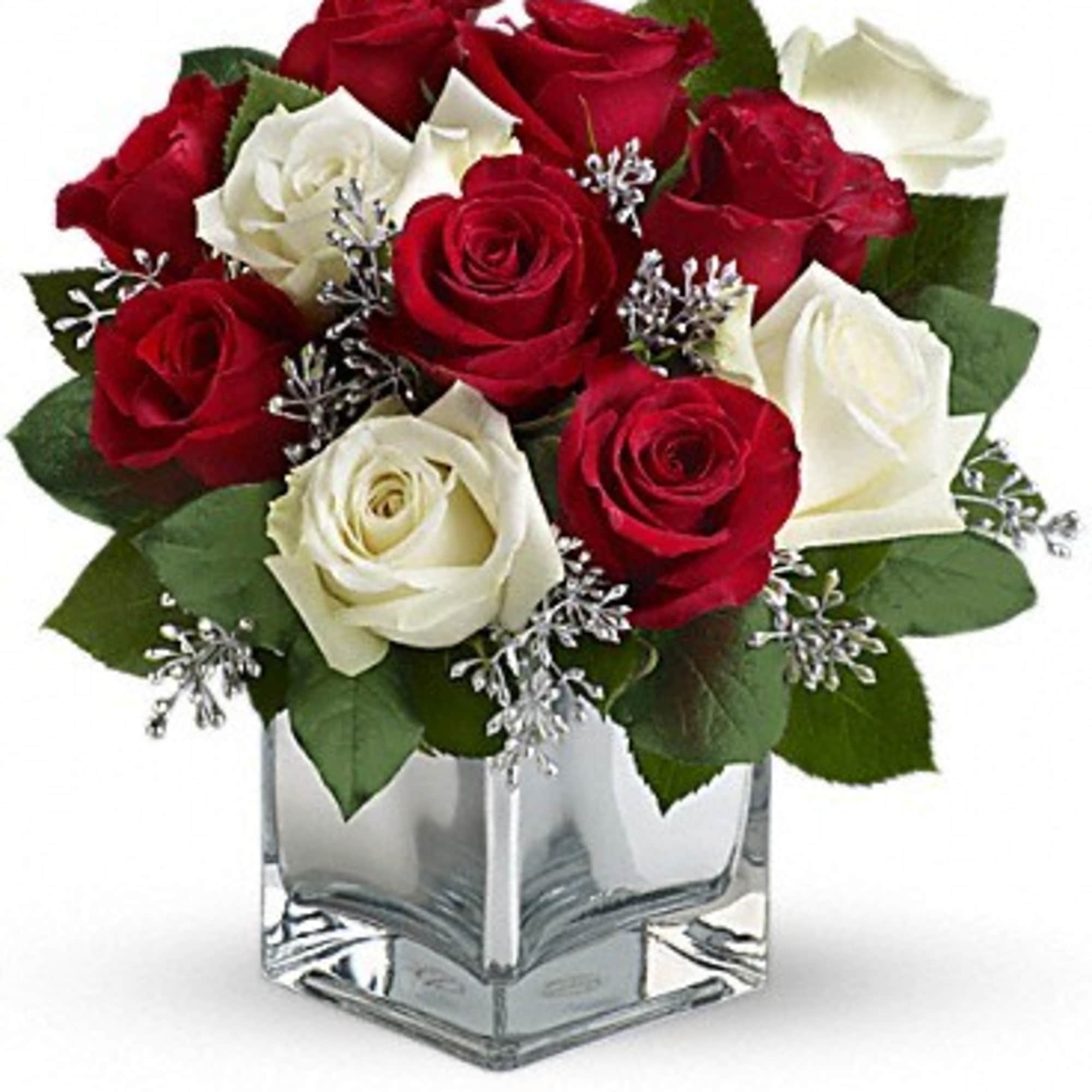 Red and white roses arranged in a clear square vase