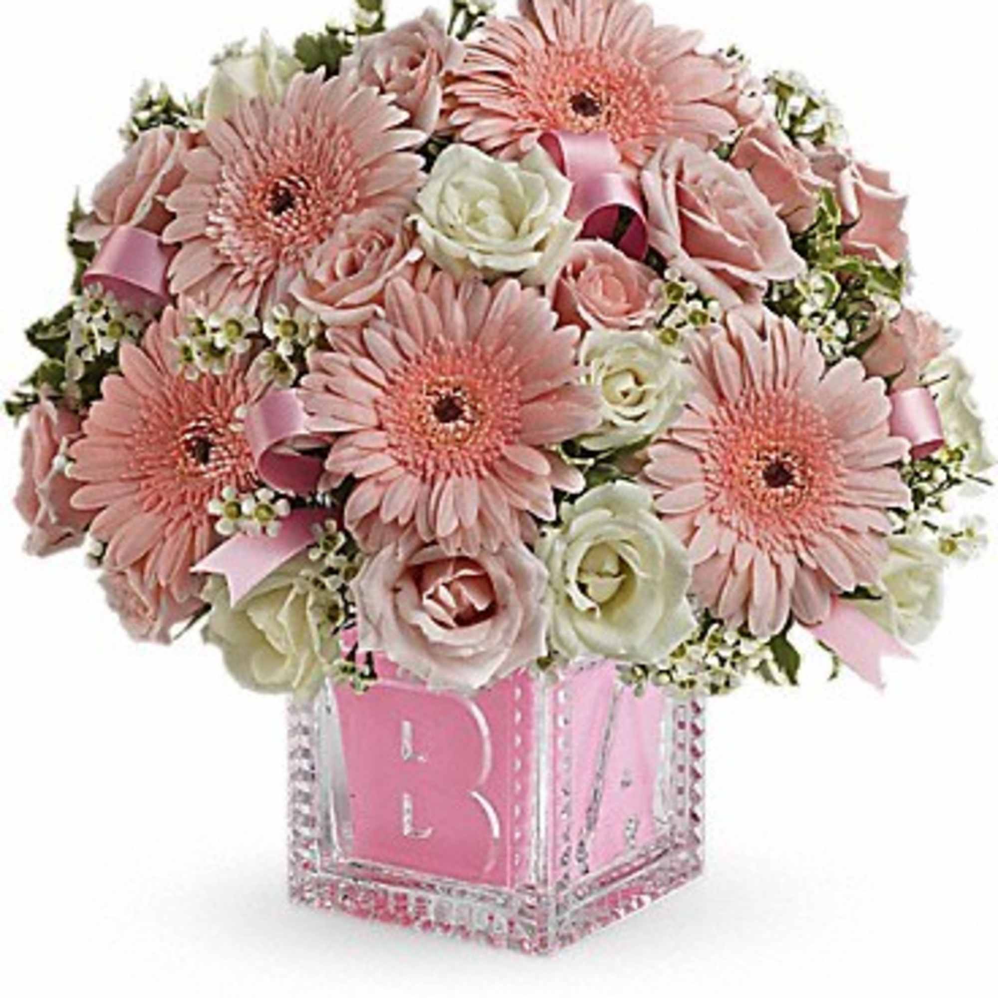 Pink gerbera daisies and roses in a clear cube vase with a pink monogram