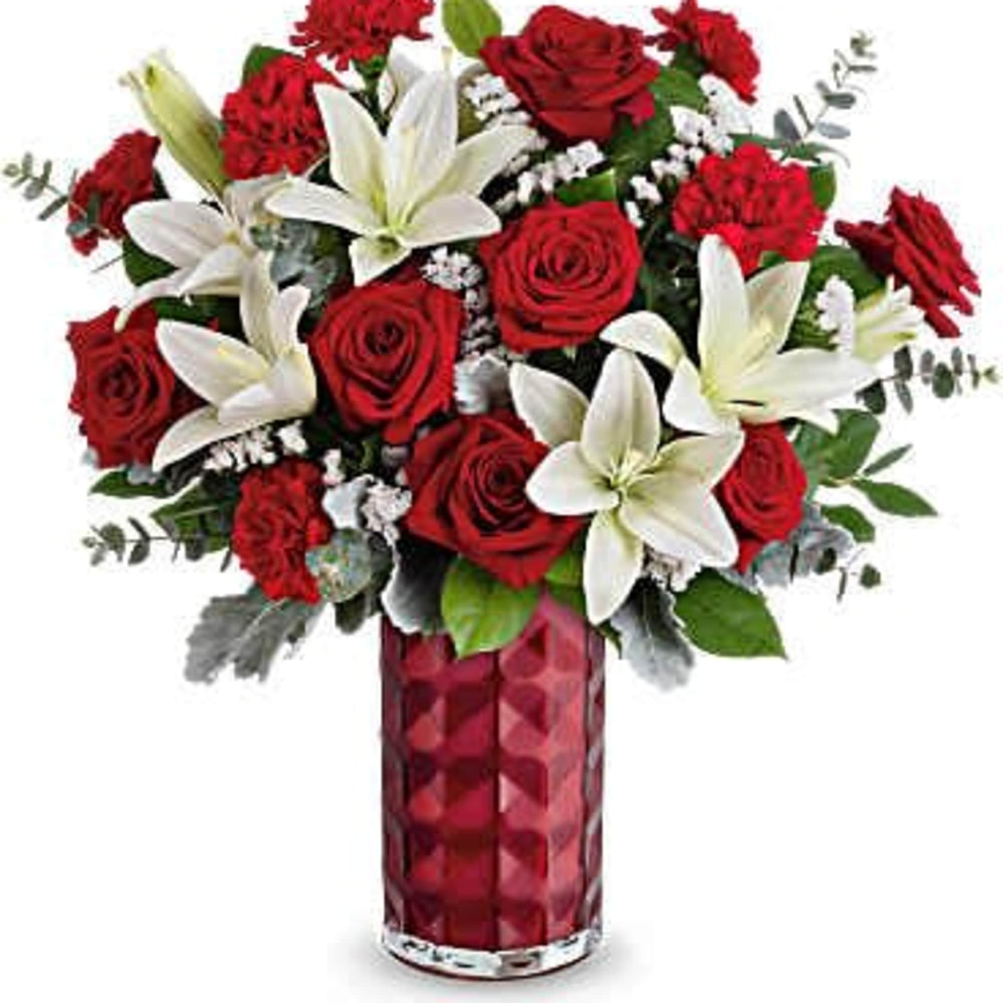 Red roses and white lilies arranged in a red glass vase