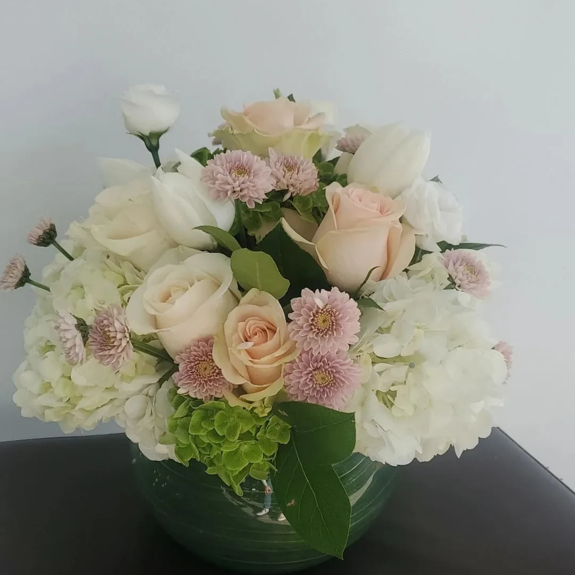 Round bouquet of white and blush flowers in a green vase