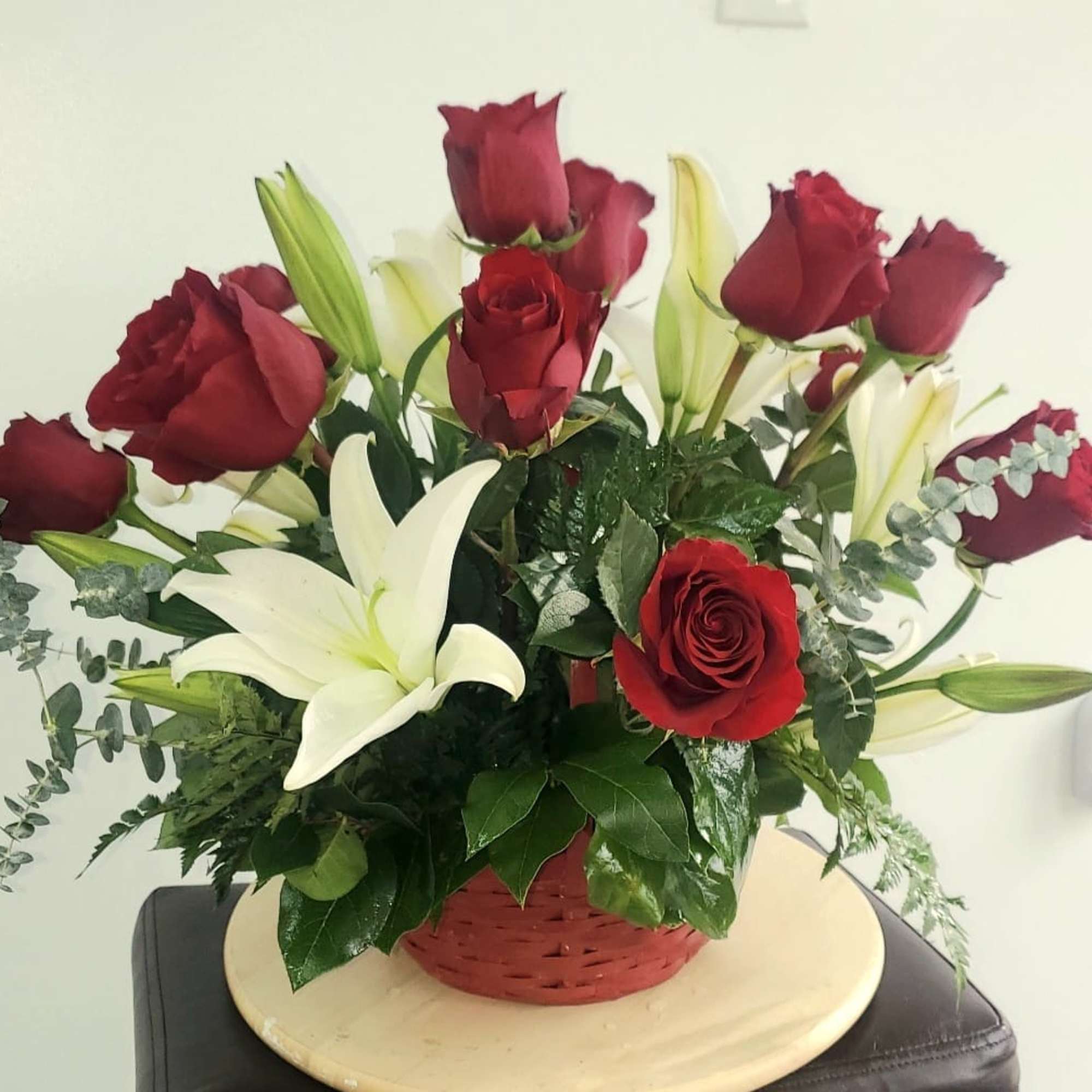 Red roses and white lilies in a red basket arrangement