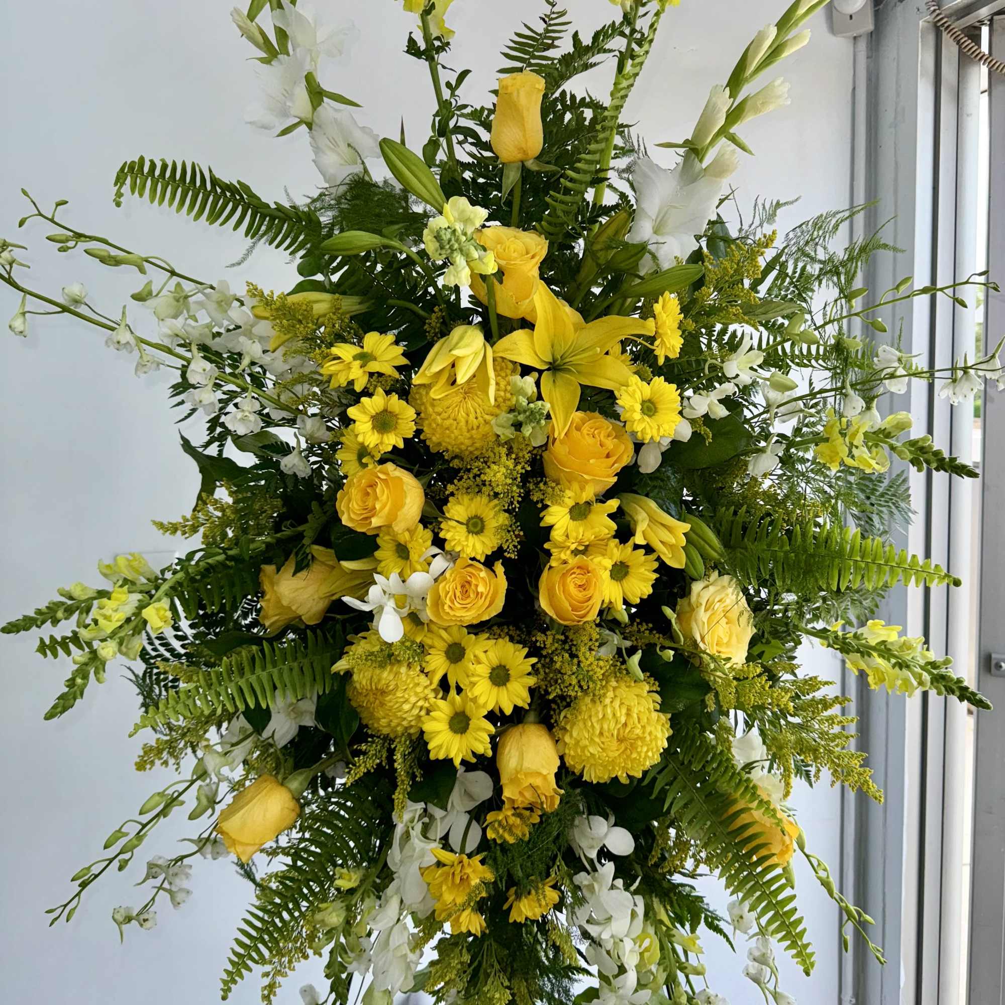 Tall yellow and white floral standing spray on a black easel, photo 2 of 2