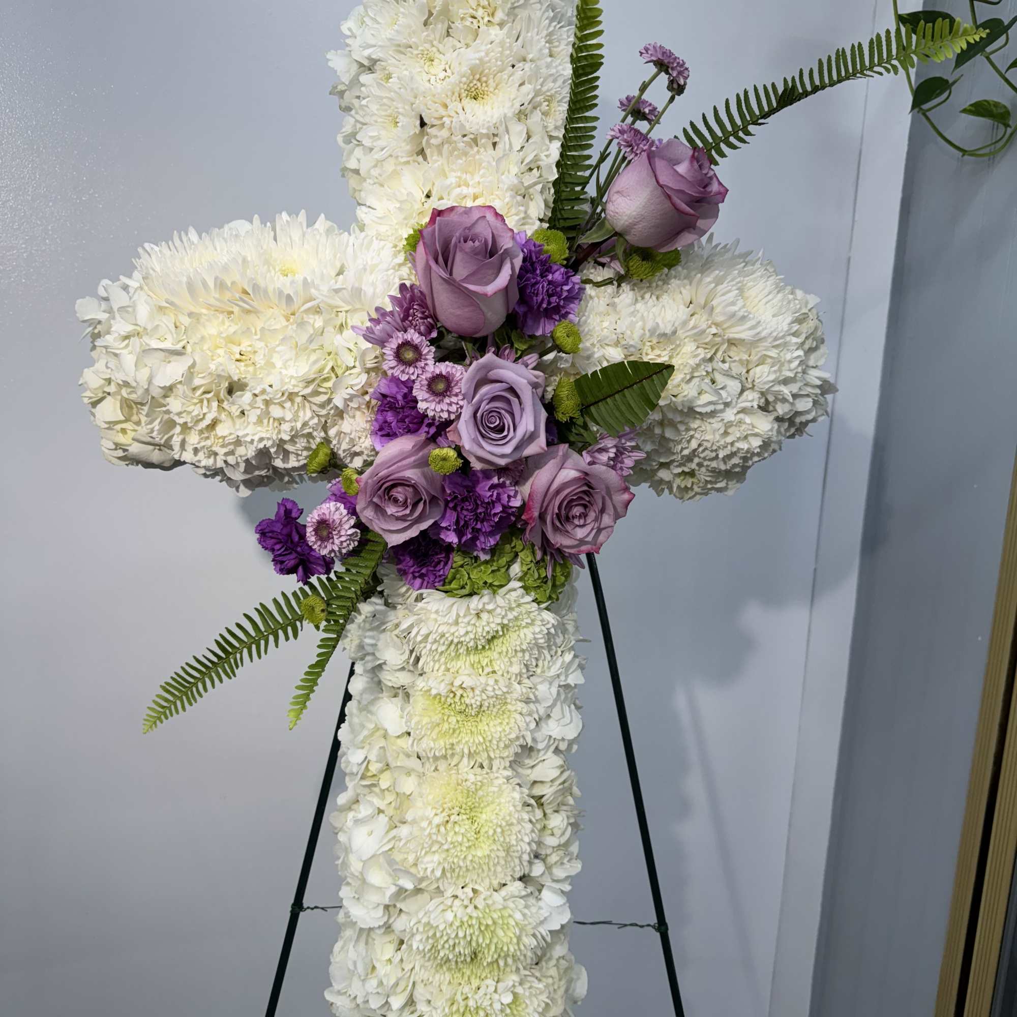 Standing floral cross with white blooms and lavender roses