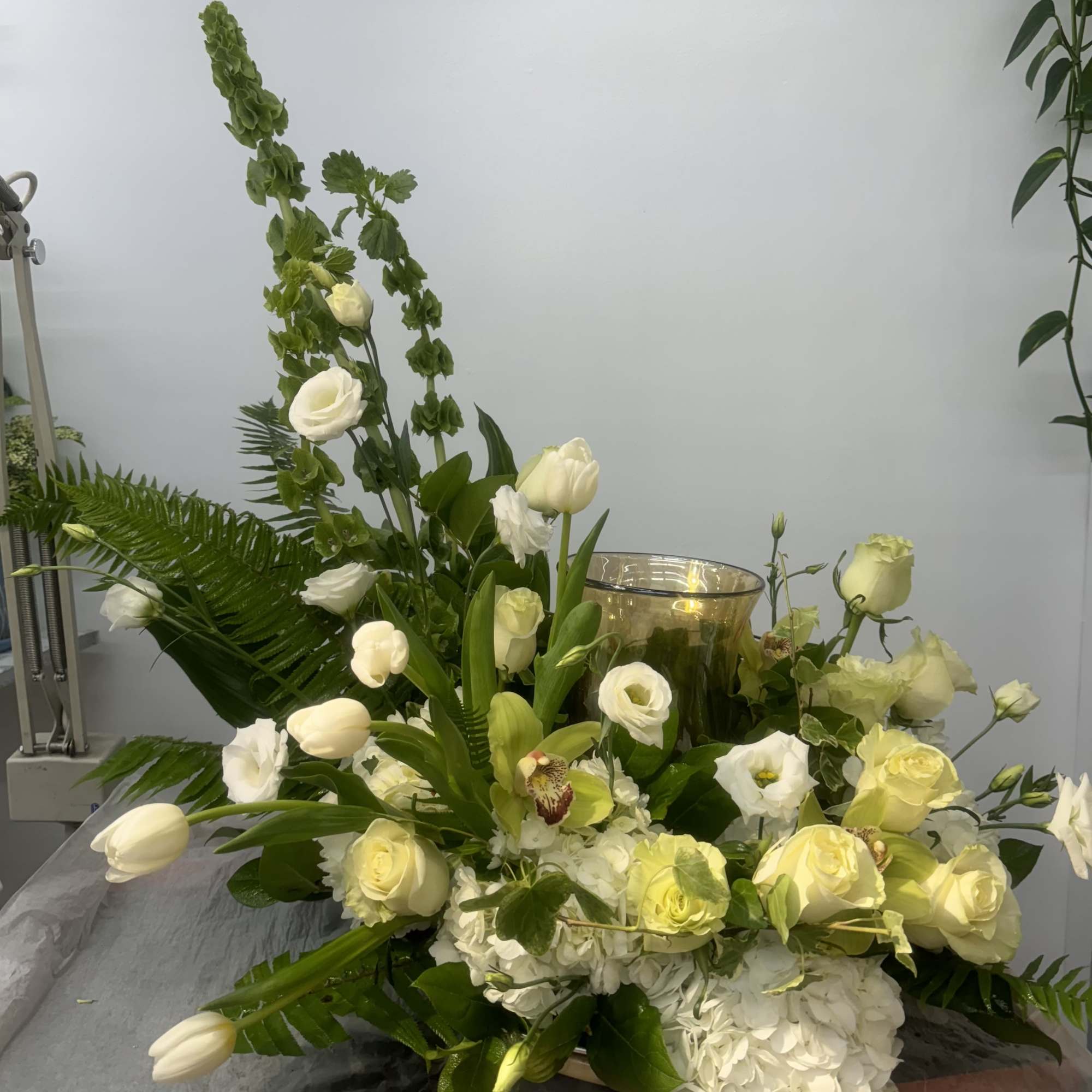 White floral arrangement with roses, tulips, and hydrangea in a glass vase