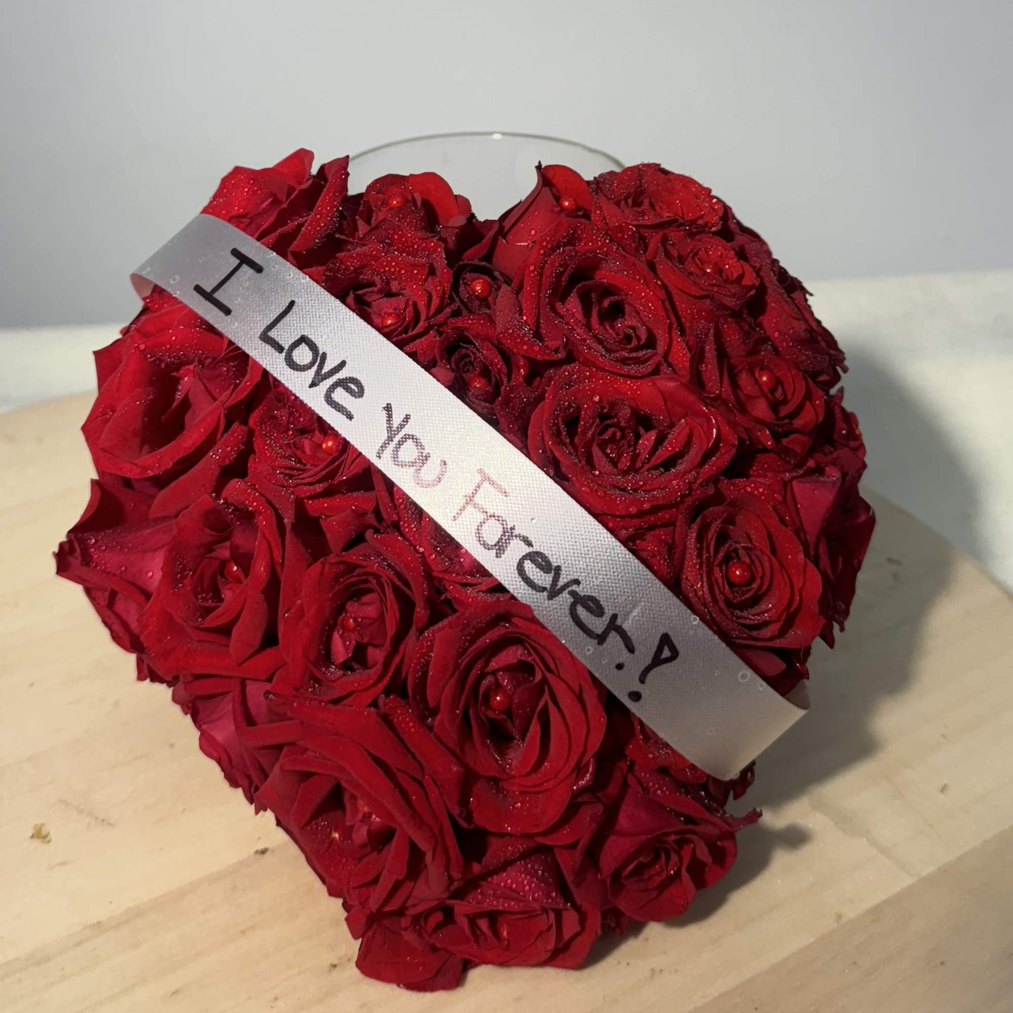 Heart-shaped bouquet of red roses with a ribbon reading "I Love You Forever"