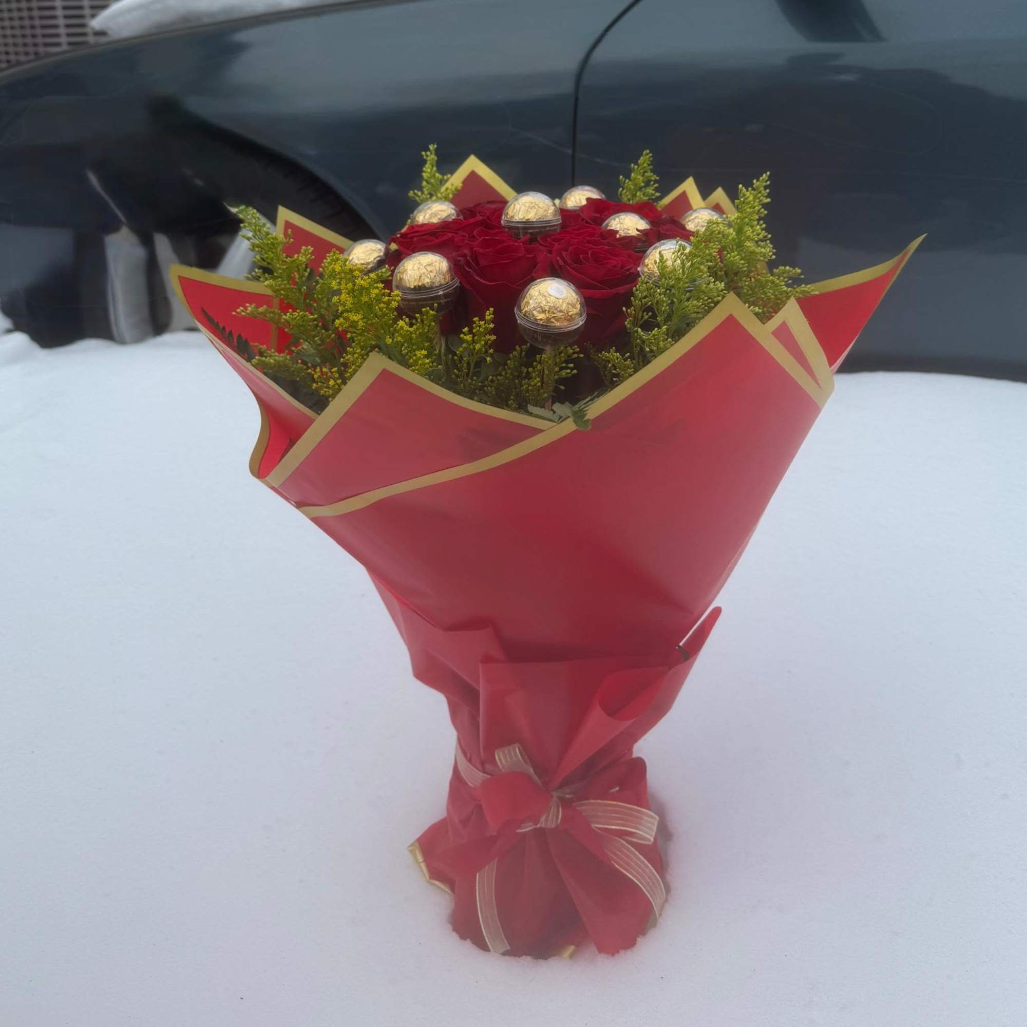 Bouquet of red roses with gold-wrapped chocolates in red paper