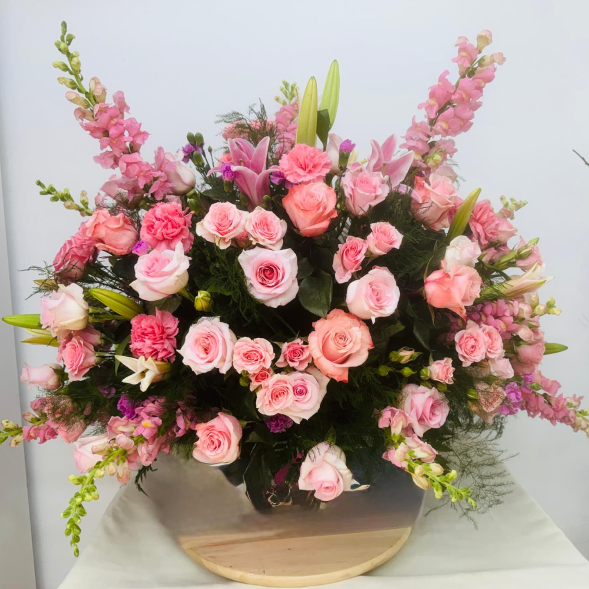Large pink floral arrangement in a black container with roses and lilies