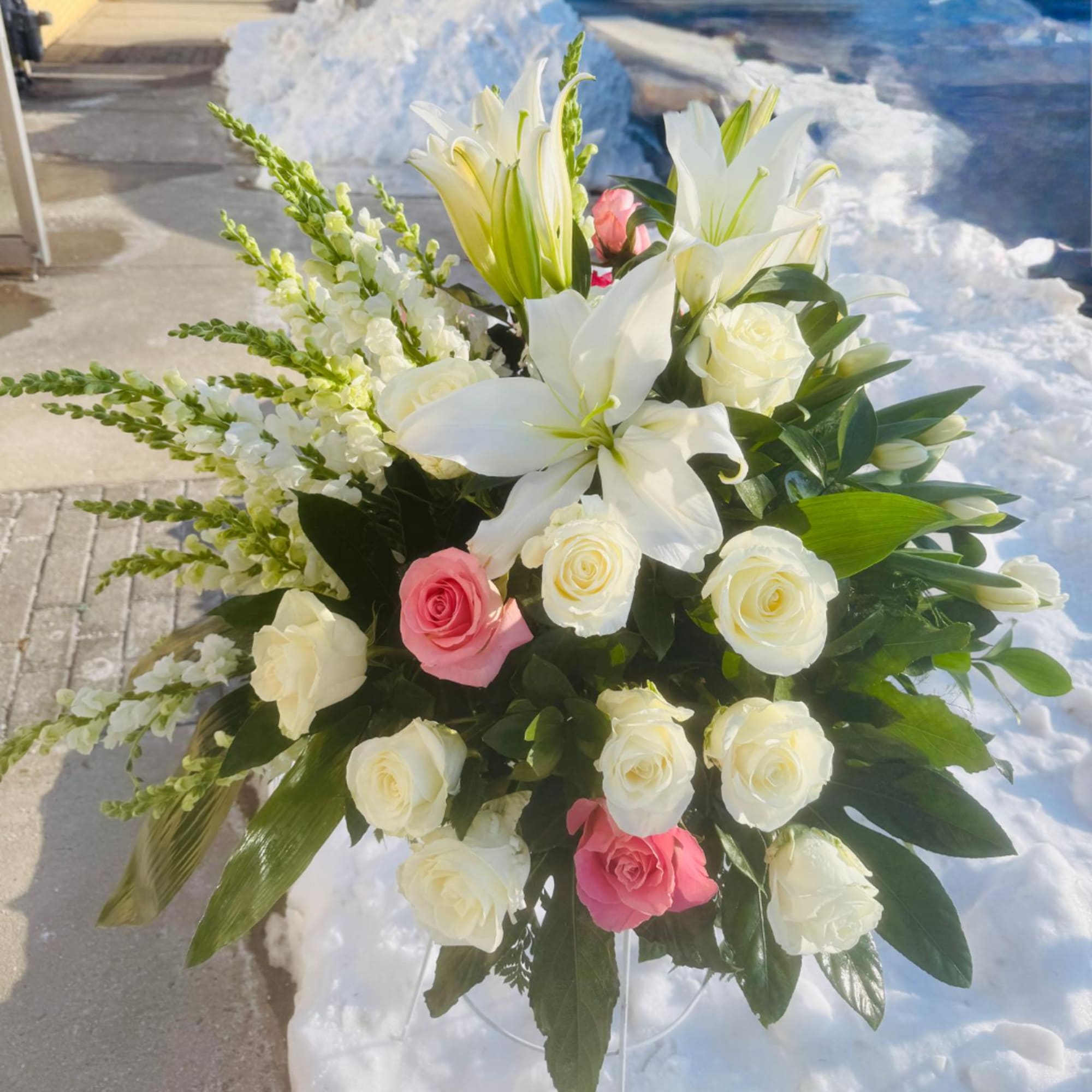 White lilies and roses with pink roses in a clear vase