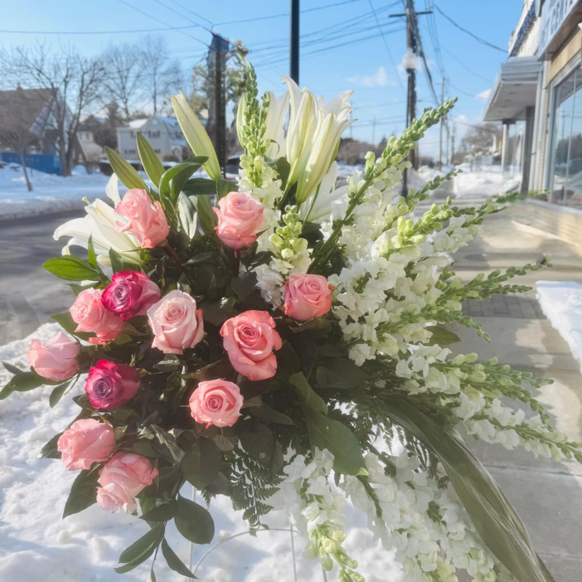 Pink and white roses with lilies and snapdragons in a large standing arrangement