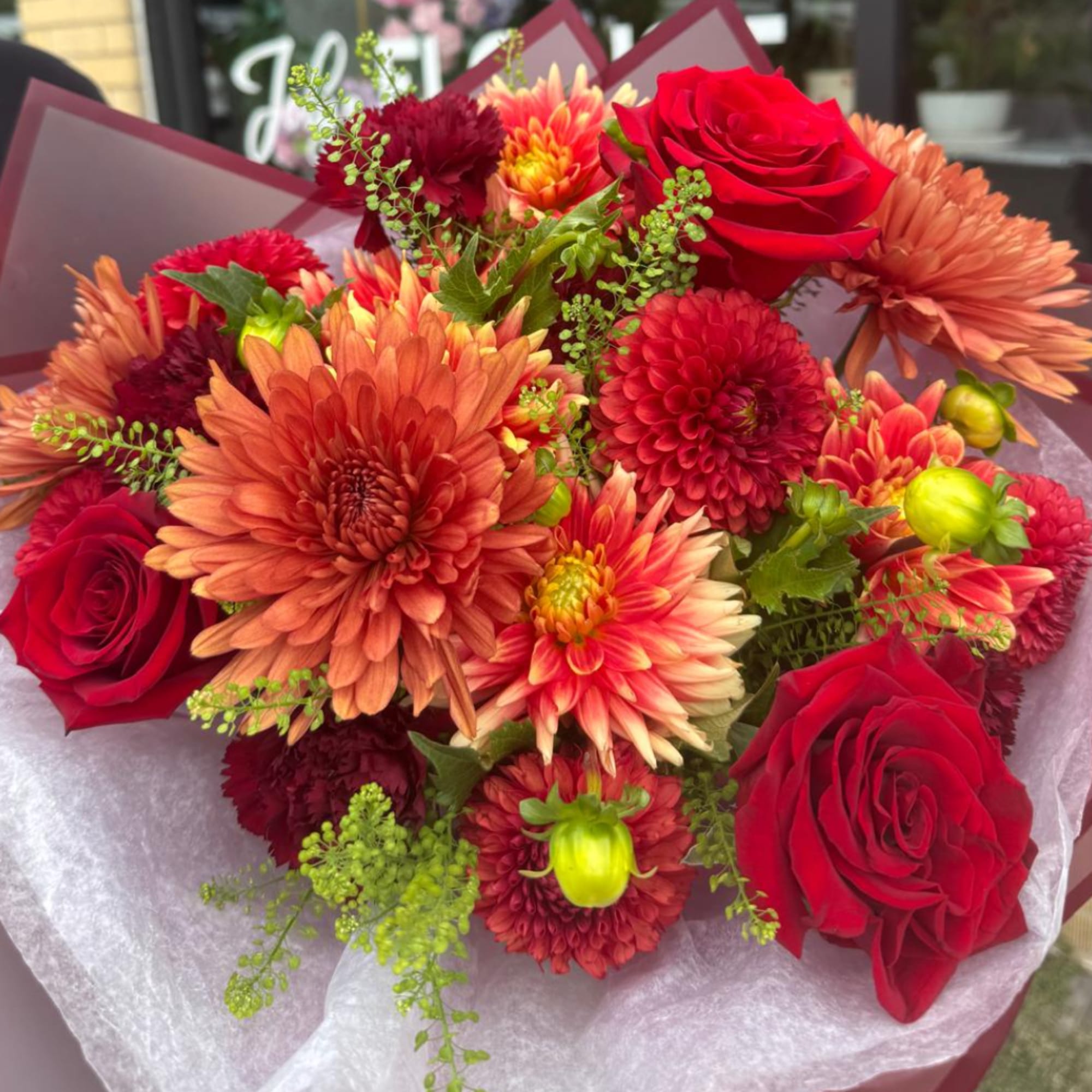 Bouquet of red roses and orange chrysanthemums wrapped in paper