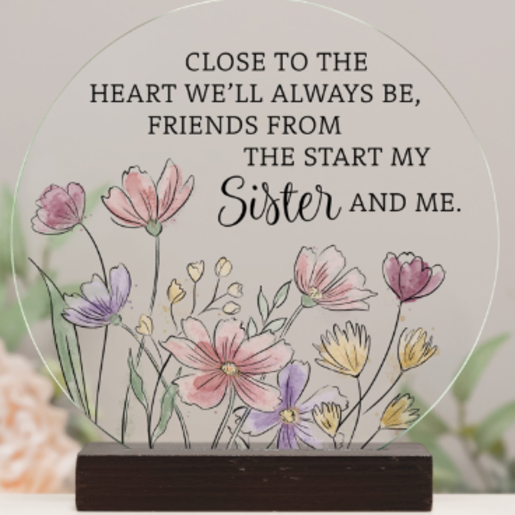 Round memorial plaque with floral illustration and sister quote on a wooden stand