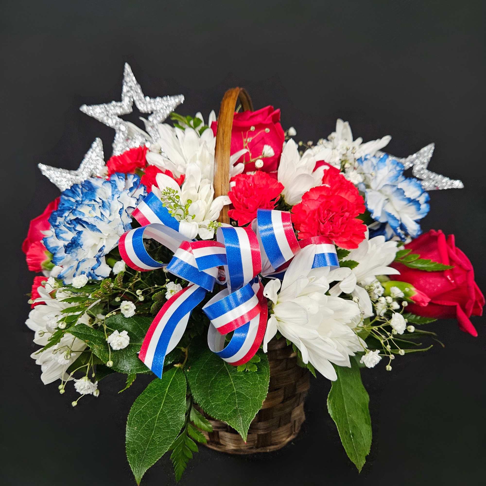 Basket of red, white, and blue flowers with star decorations and ribbon
