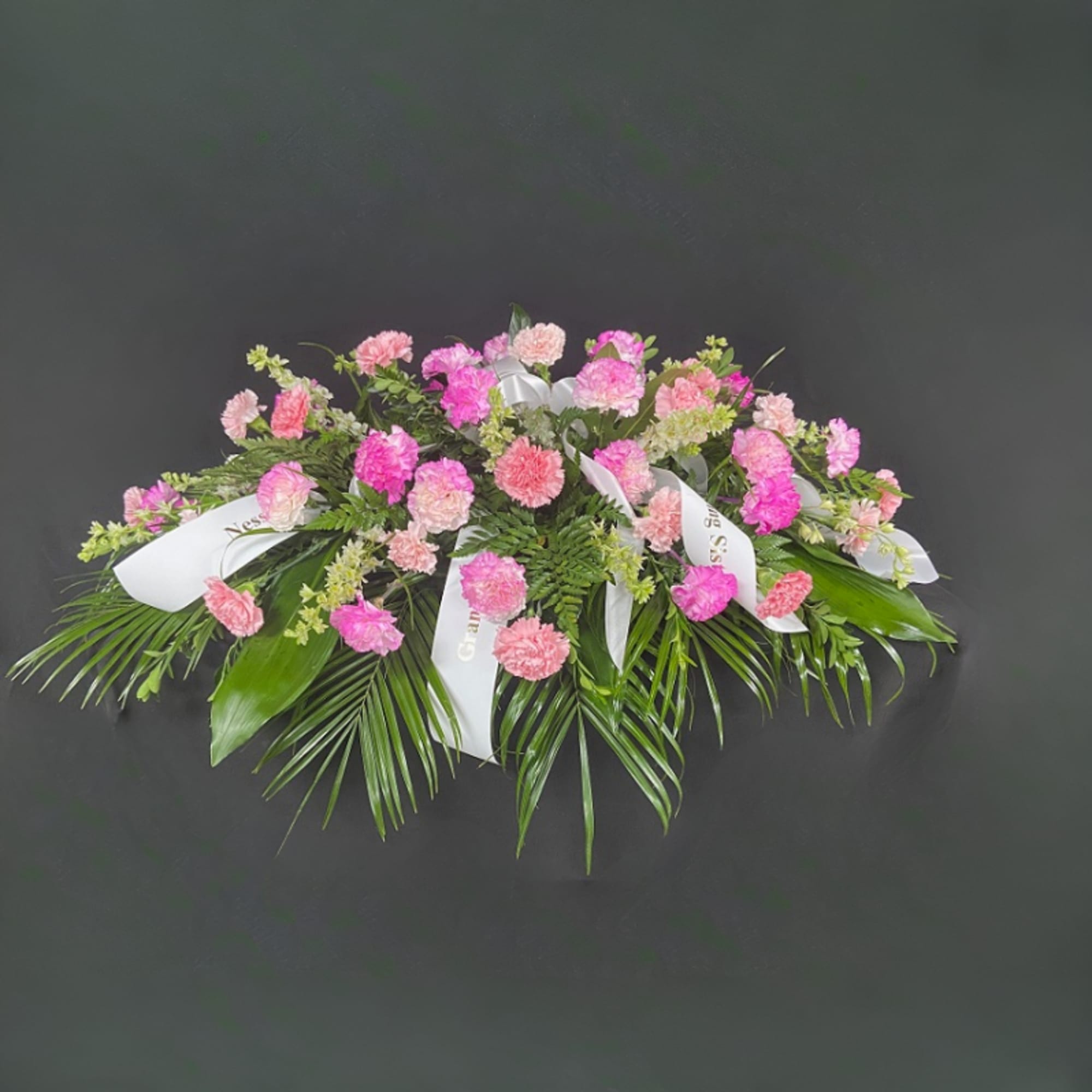 Pink carnation spray with white ribbons and palm fronds