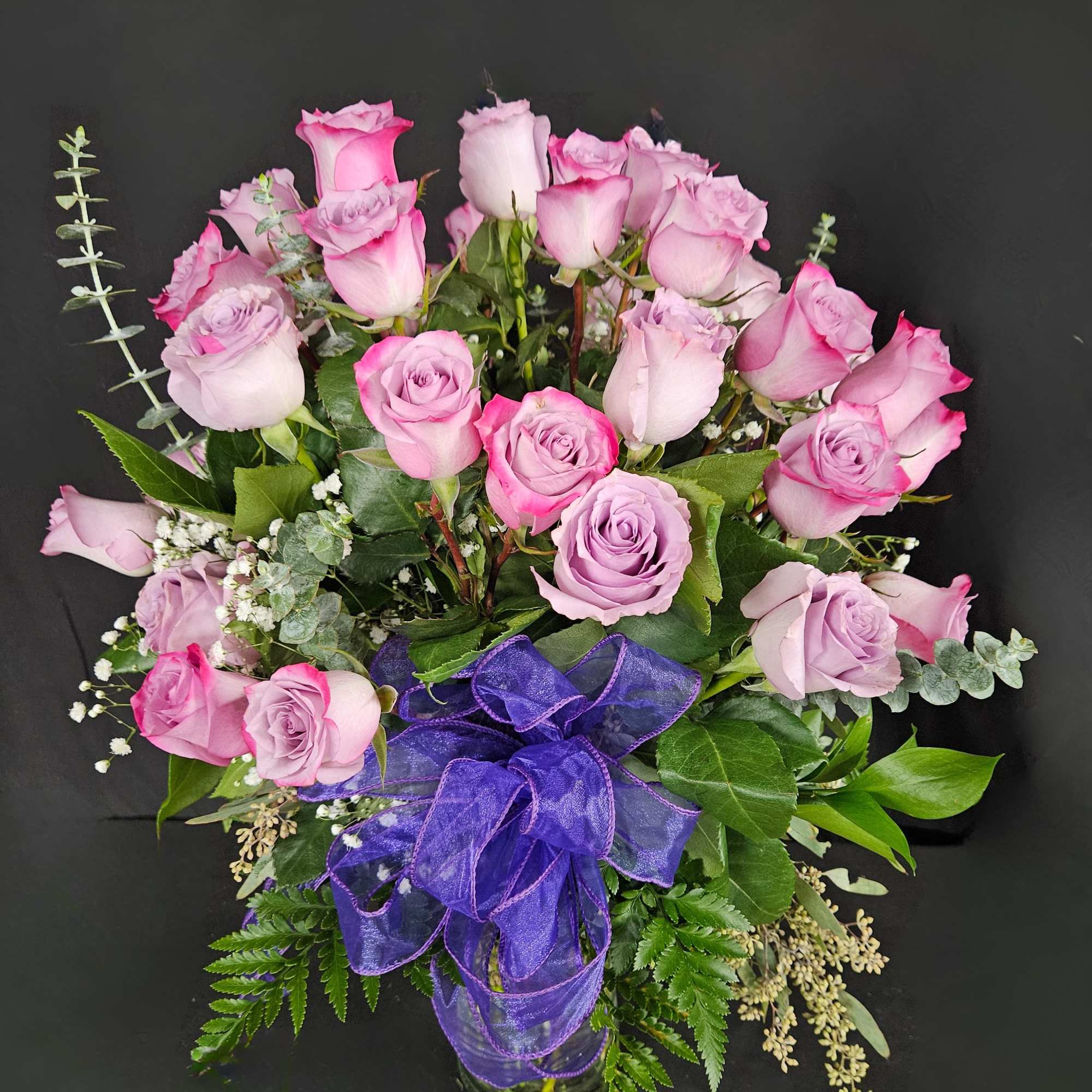 Bouquet of pink and lavender roses with a purple ribbon