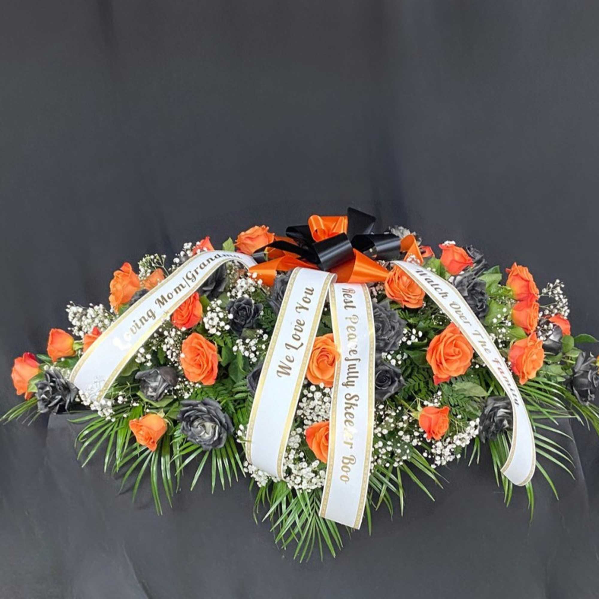 Orange and black rose funeral spray with memorial ribbons