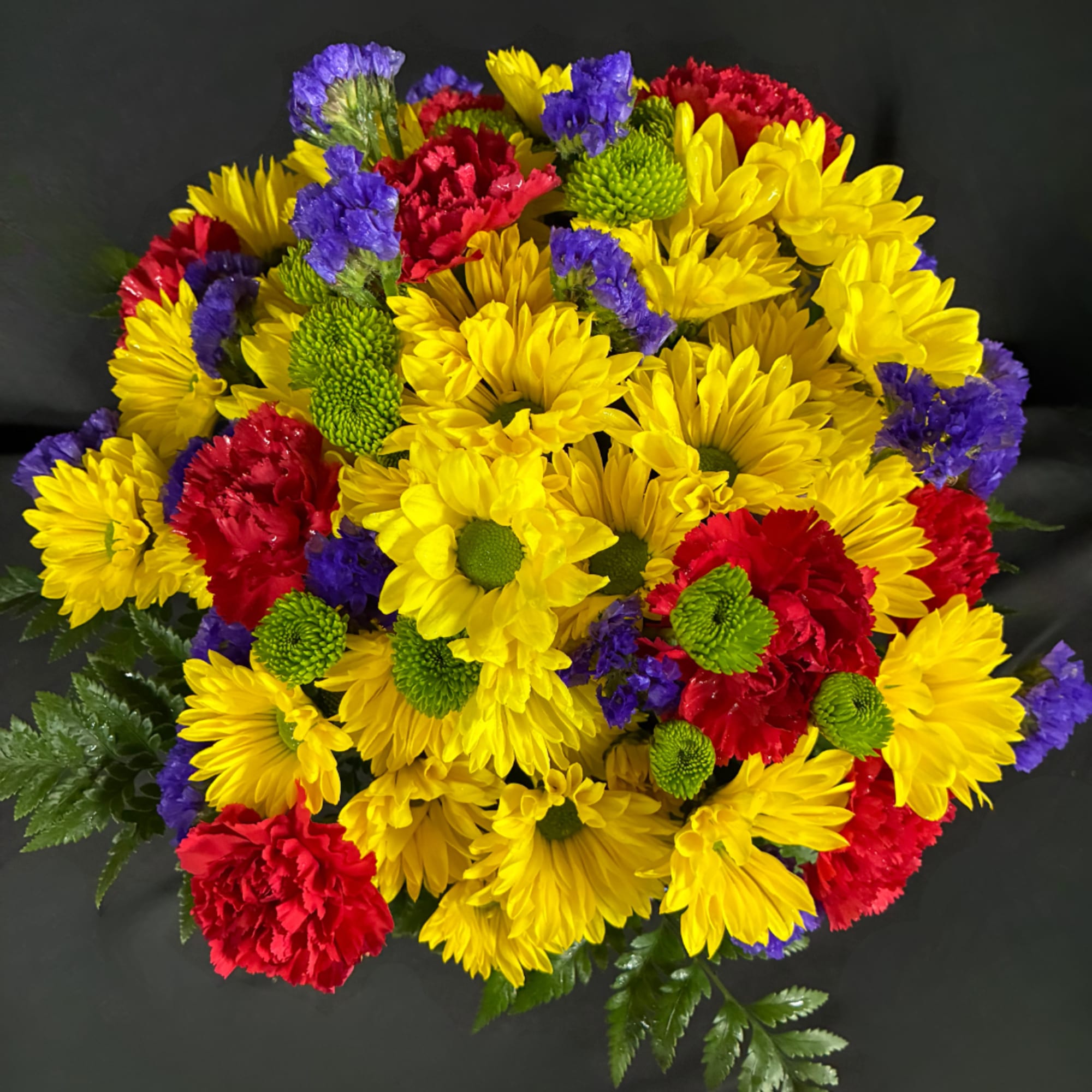 Bright mixed bouquet of yellow daisies, red carnations, and purple filler flowers