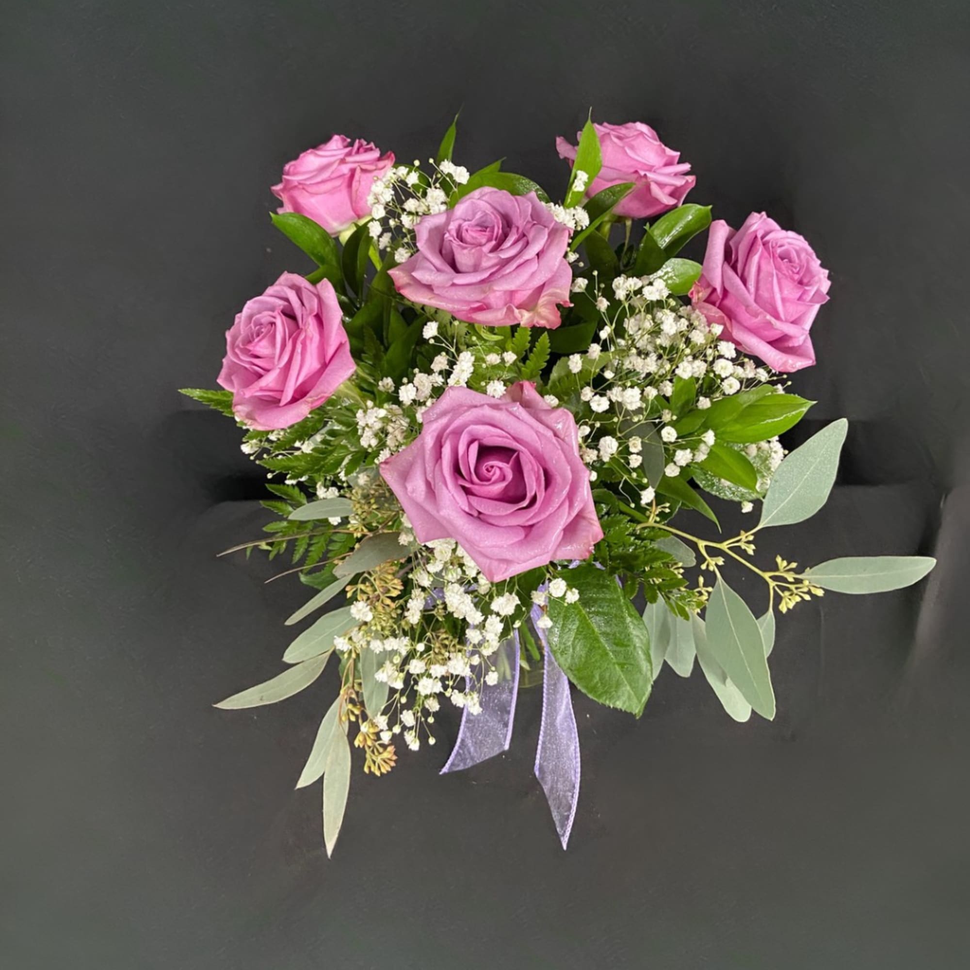 Pink roses with baby's breath and greenery tied with a purple ribbon