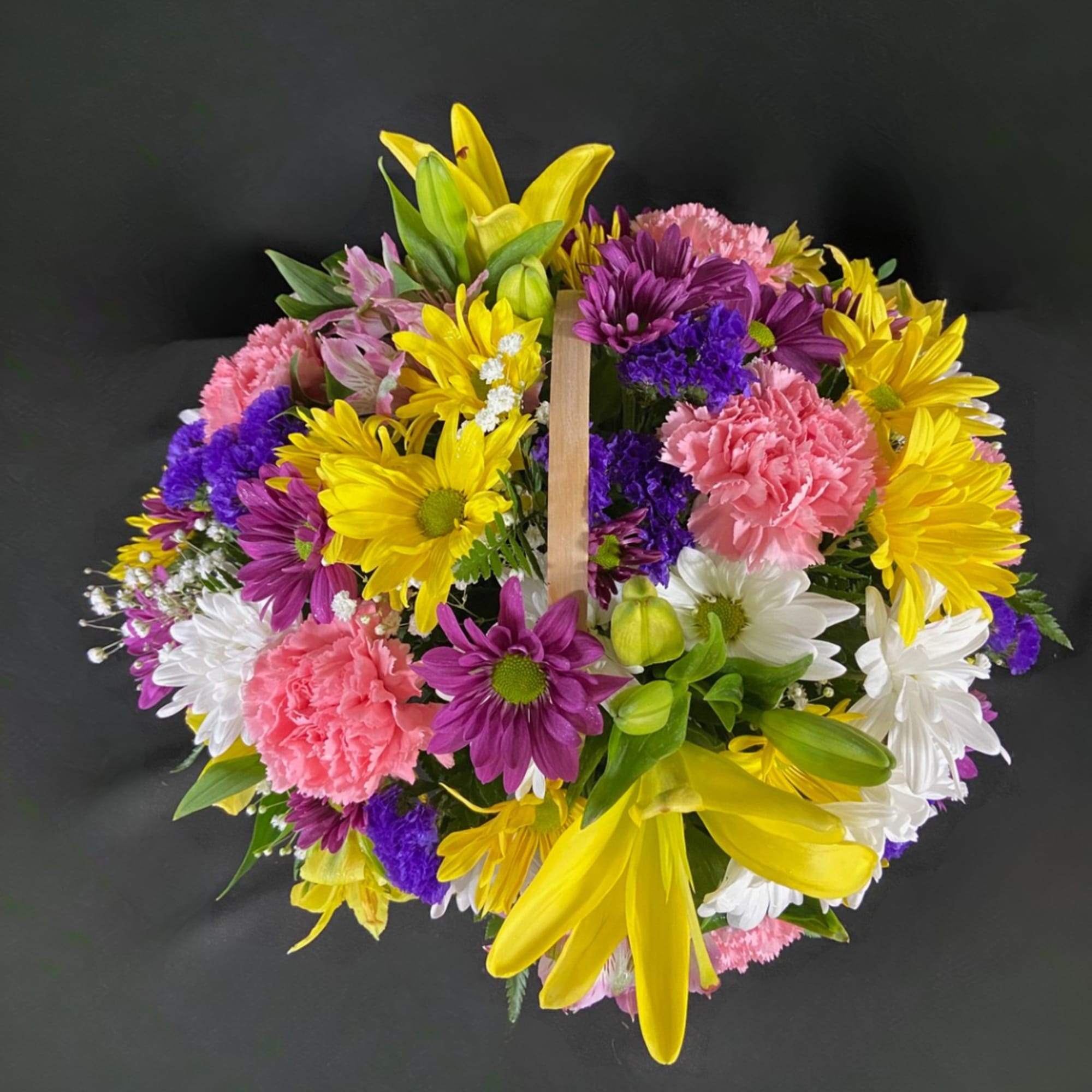 Colorful mixed flower basket with yellow lilies, daisies, and pink carnations