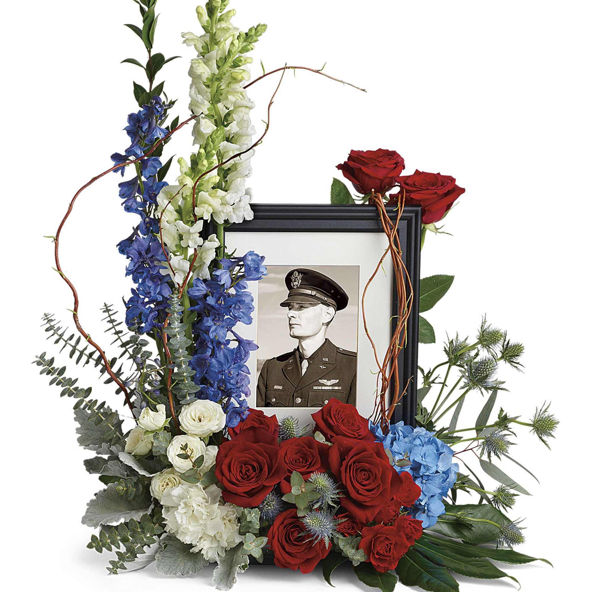 Floral tribute around a framed black-and-white portrait with red roses and blue and white flowers
