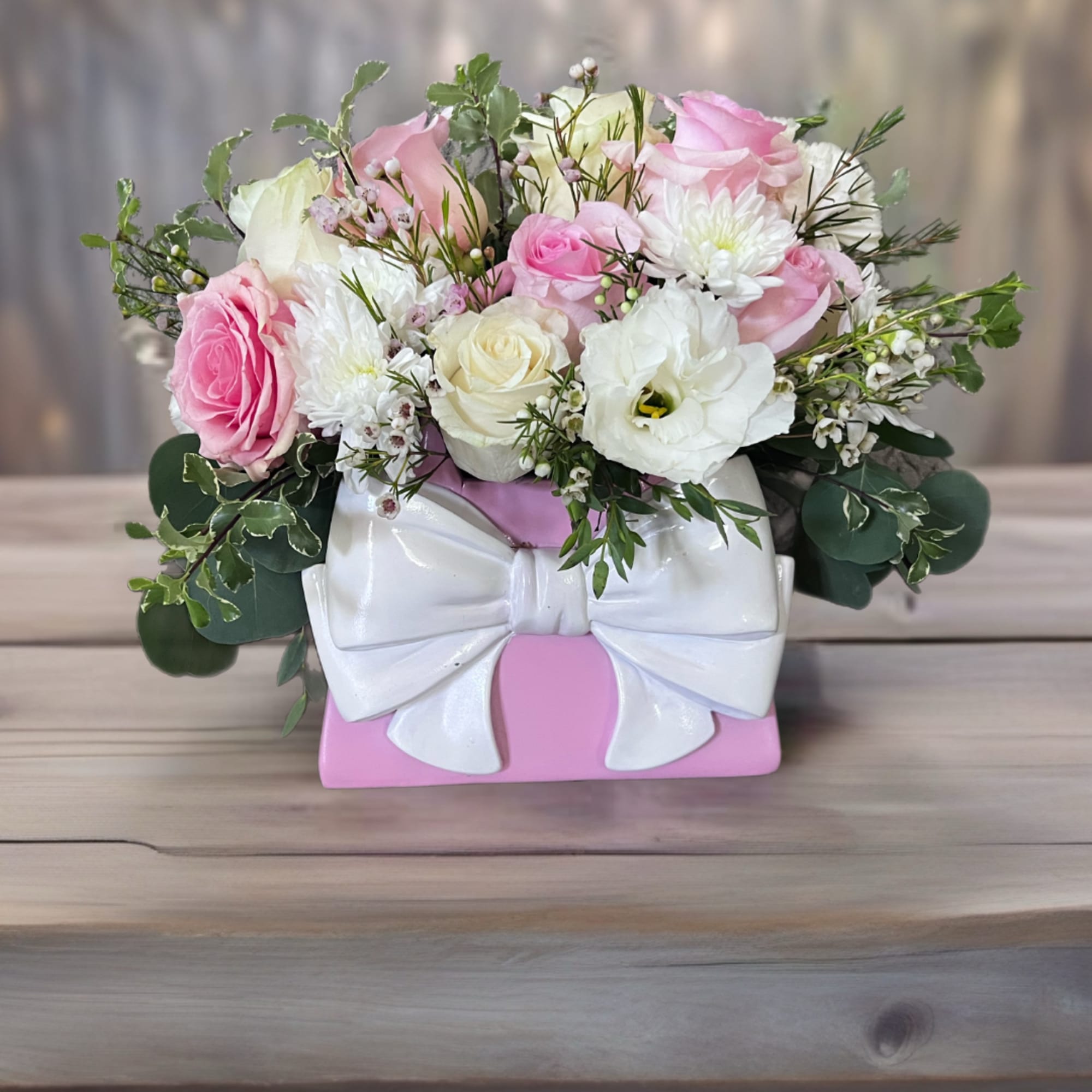 Pink and white roses arranged in a pink gift box with a white bow