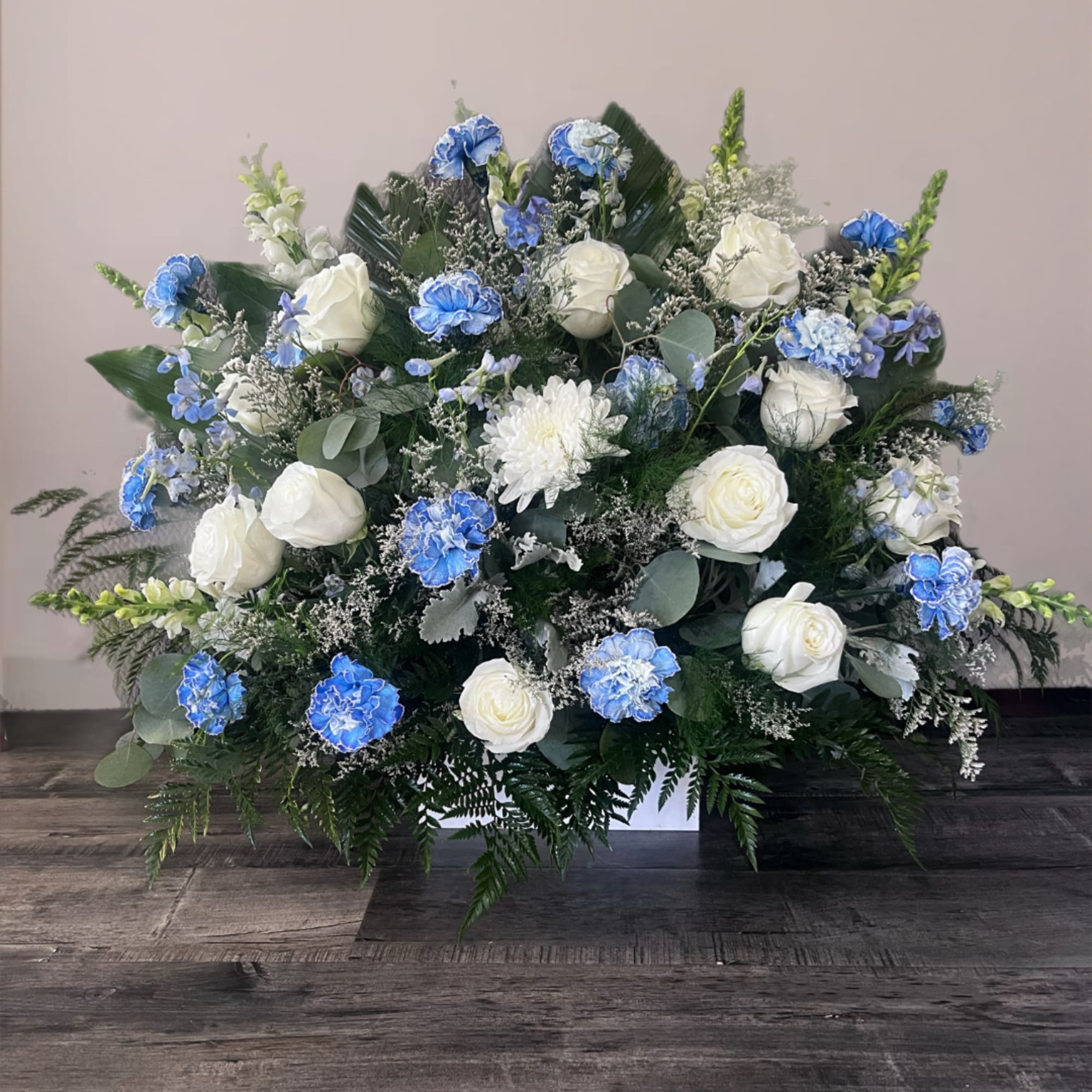 White roses and blue carnations in a low rectangular arrangement