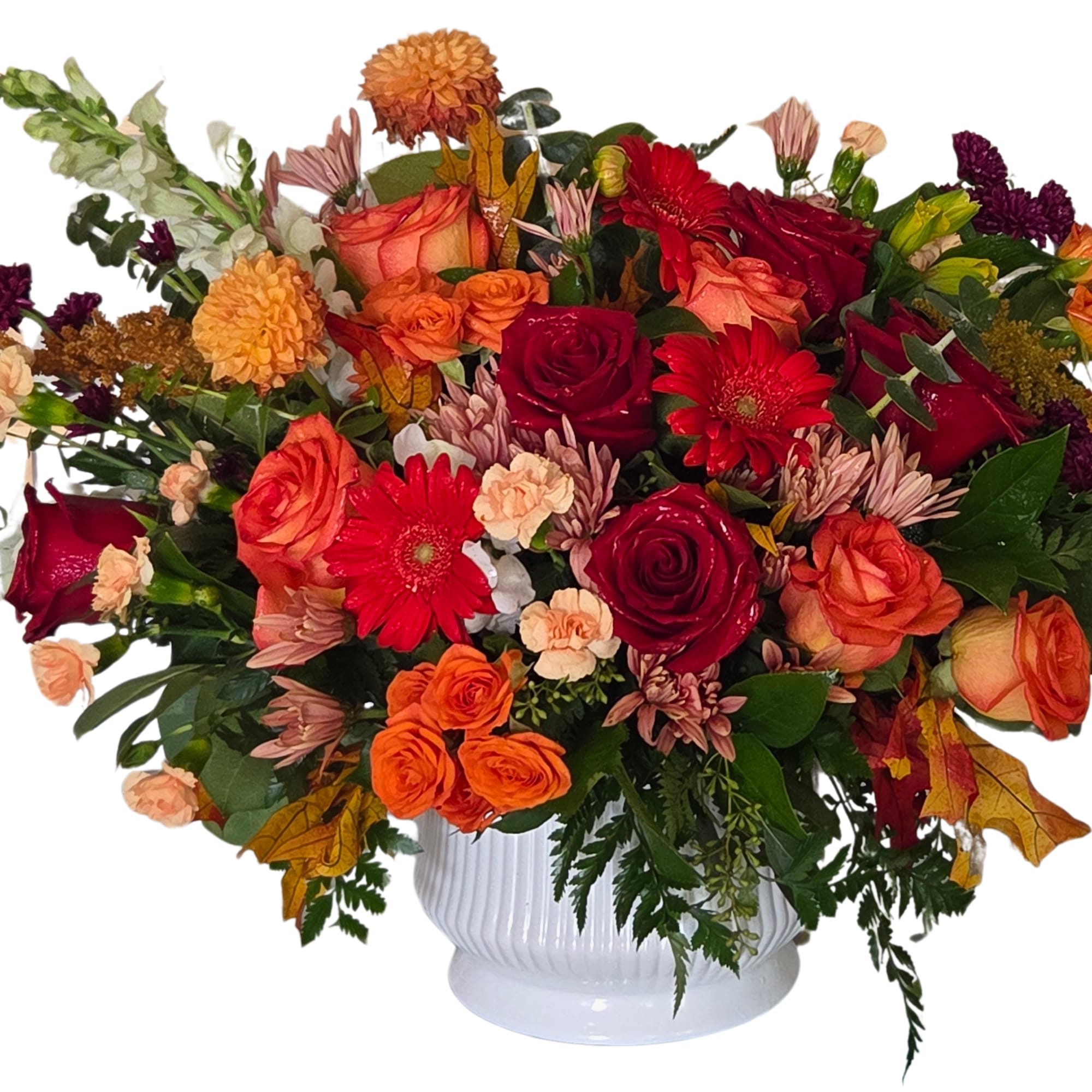 Mixed bouquet of red, orange, and peach flowers in a white vase